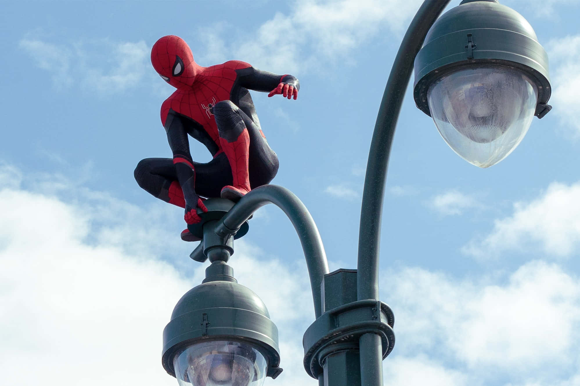 Spider Man No Way Home 桌布 壁紙 — 蜘蛛人蹲在路燈頂上，背景是明亮的藍天和蓬鬆的白雲。