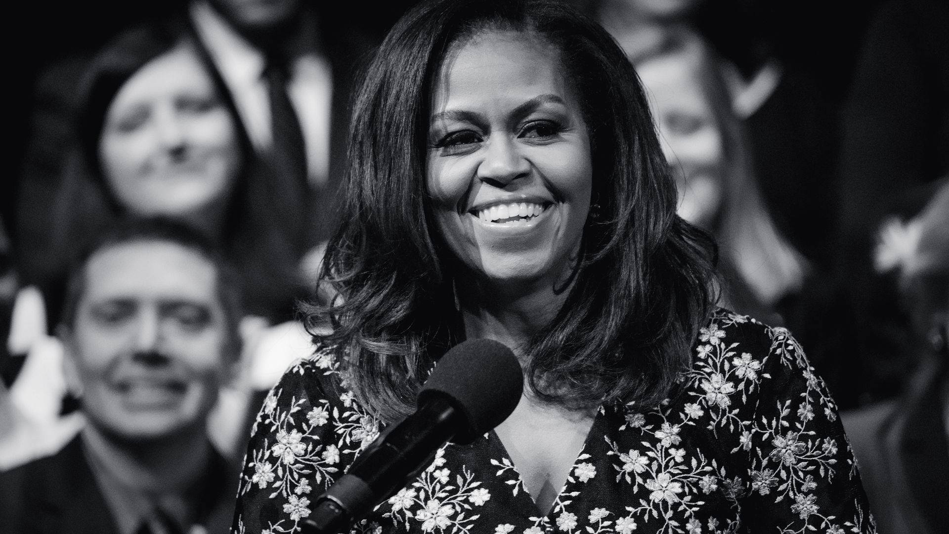 Michelle 桌布 壁紙 — 蜜雪兒·歐巴馬在黑白公開活動中對著麥克風溫暖微笑地說話。
