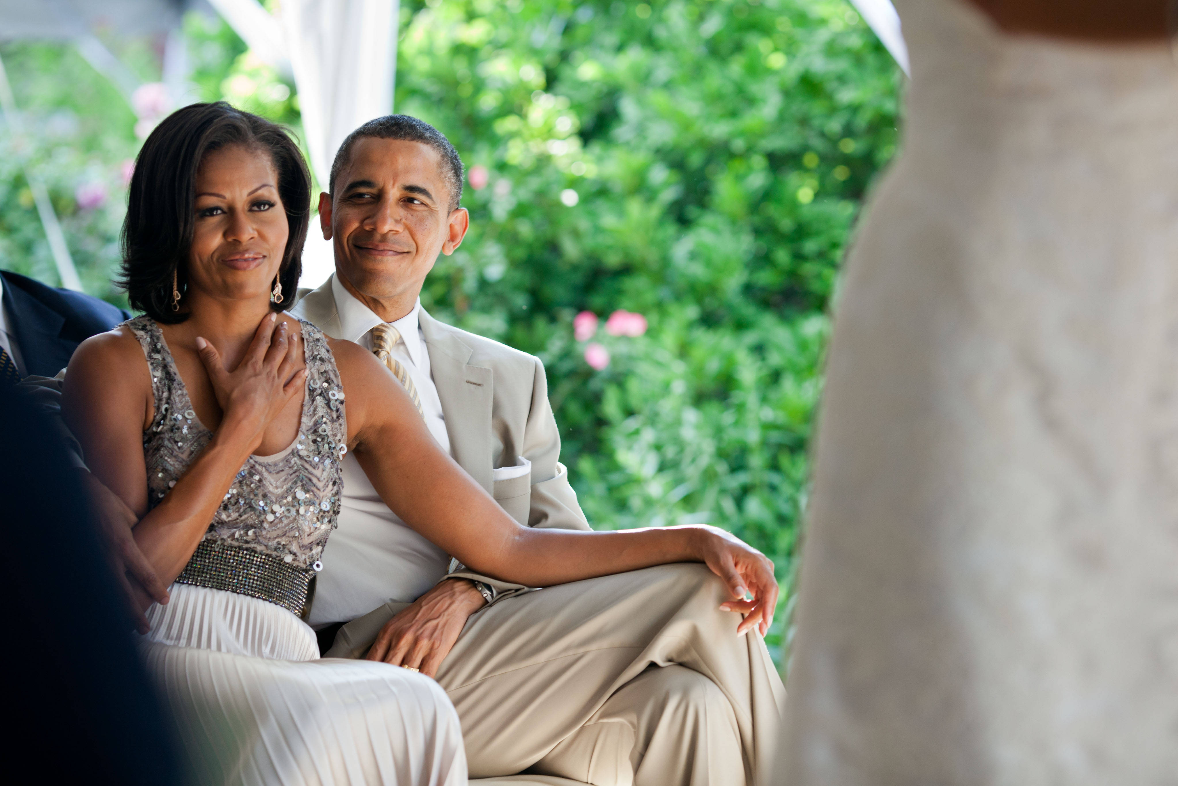 Michelle 桌布 壁紙 — 蜜雪兒和巴拉克·歐巴馬在茂密的綠色花園中一起坐著，溫暖地微笑。