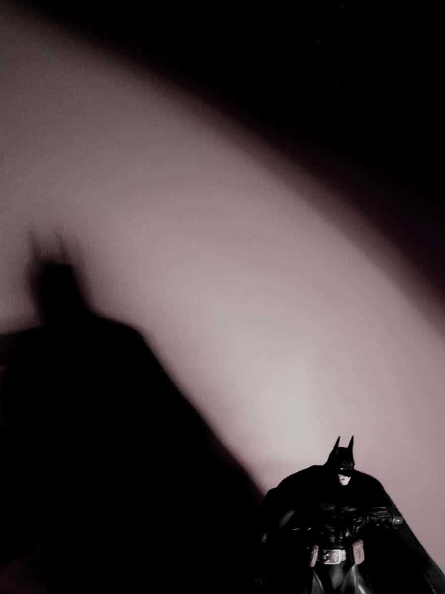 Shadow Of The Bat 桌布 壁紙 — 蝙蝠俠人偶在柔和燈光的牆壁上投射出戲劇性的陰影，營造出陰鬱的電影感場景。