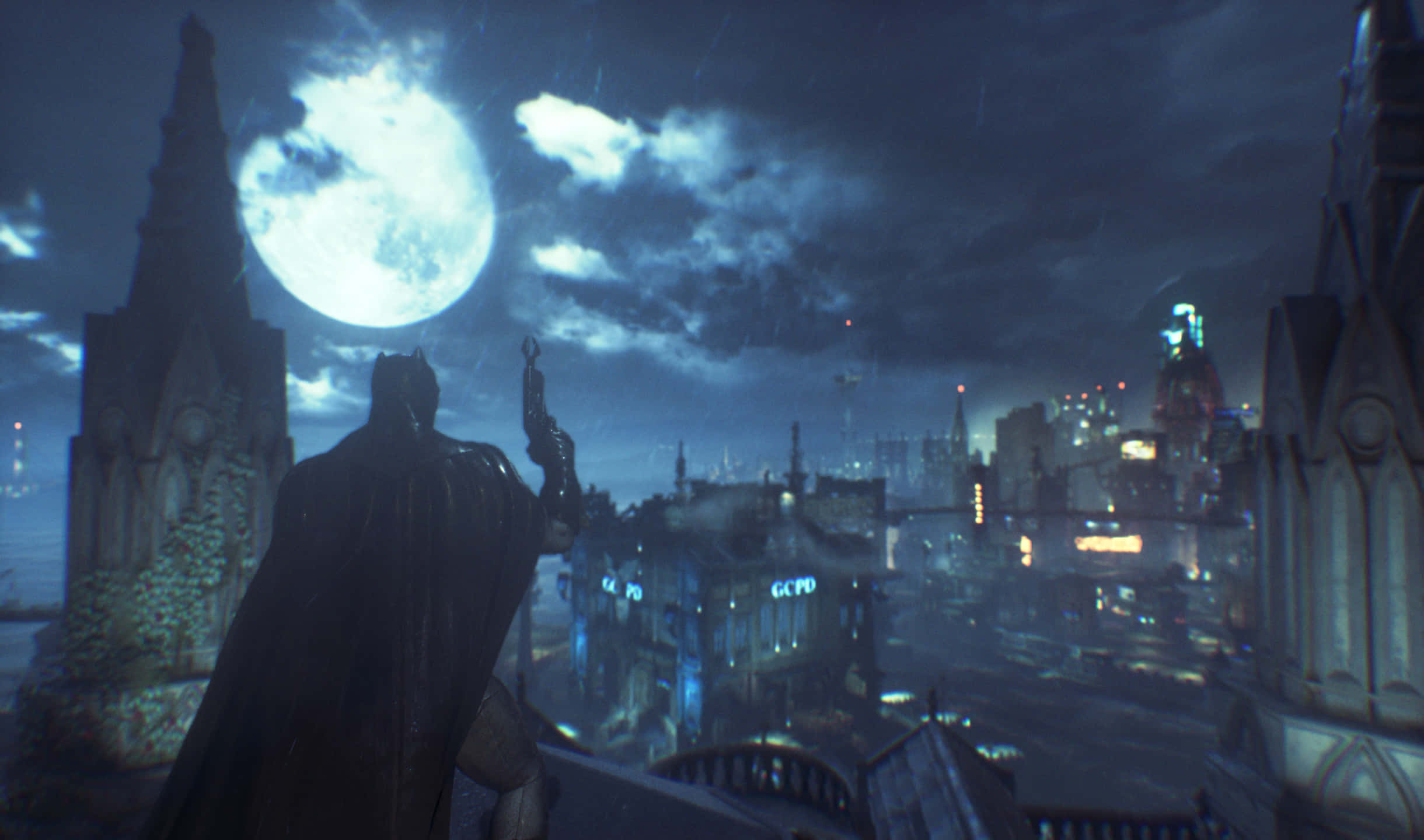 2440x1440 Batman Arkham City 桌布 壁紙 — 蝙蝠俠以剪影姿態站在哥德式屋頂上，俯瞰著在巨大發光月亮下、被雨水浸濕的高譚市天際線。