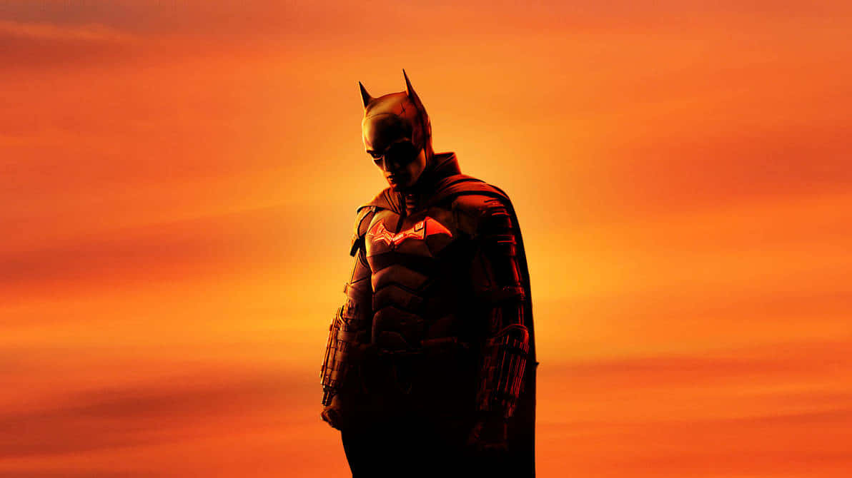 Bruce Wayne 桌布 壁紙 — 蝙蝠俠以剪影姿態站立在火紅橙色夕陽天空前，披風飄揚，帶著莊嚴的決心向下凝視。