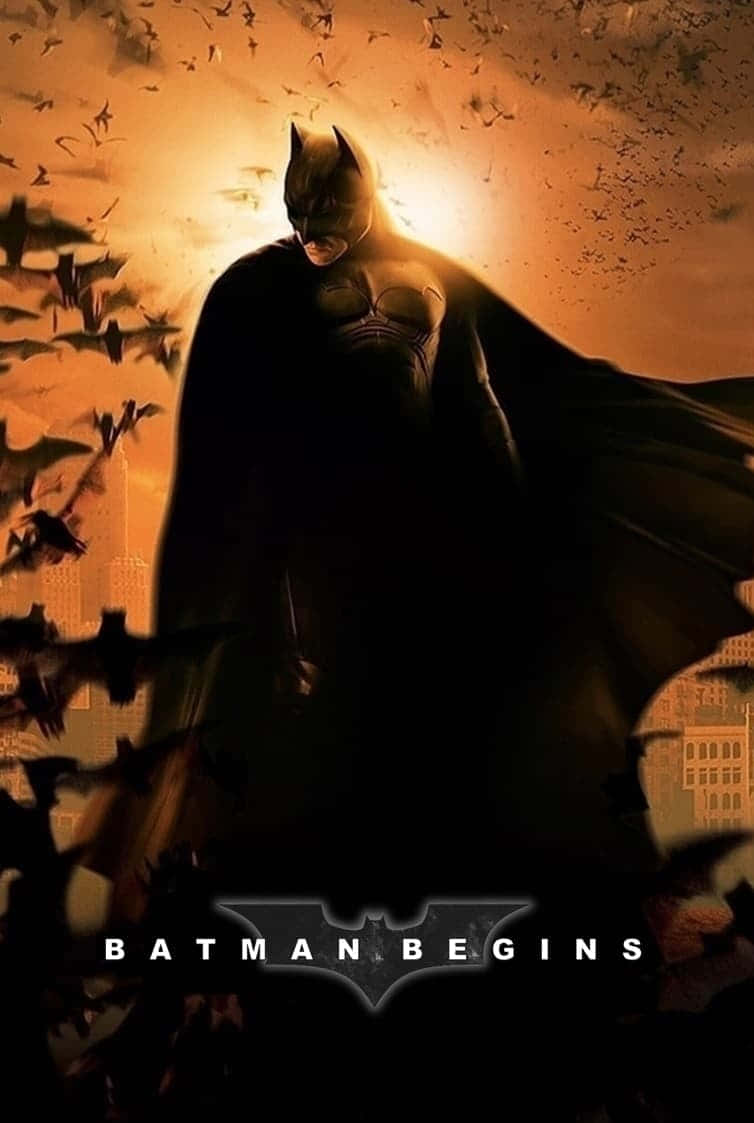 Batman Begins 桌布 壁紙 — 蝙蝠俠以剪影姿態站立在發光的橙色天空前，蝙蝠在他周圍於城市景觀上空盤旋。