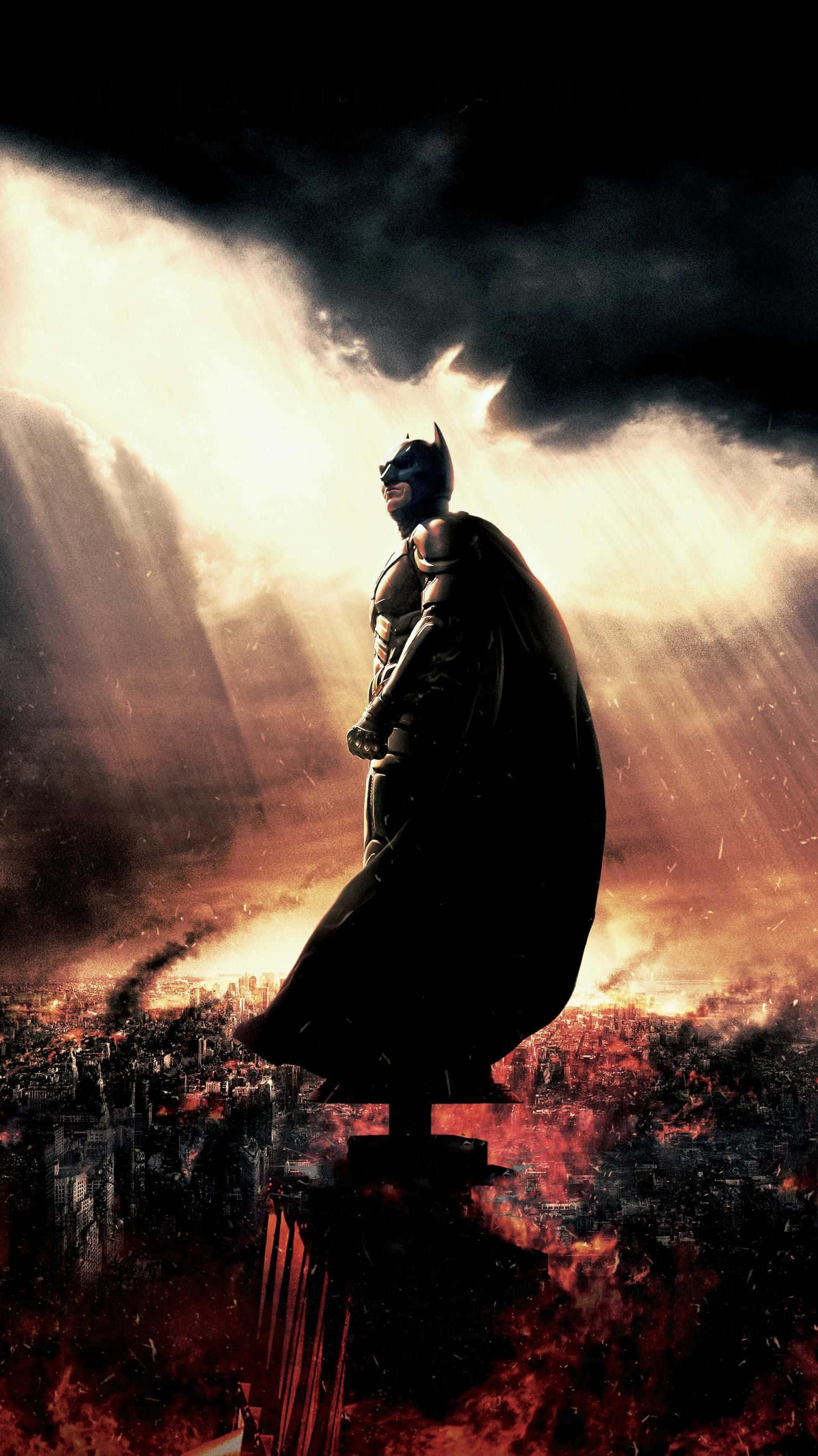 Batman Arkham Knight 桌布 壁紙 — 蝙蝠俠以剪影姿態站立於燃燒的城市景觀前，背後戲劇性的陽光穿透暴風雲層。