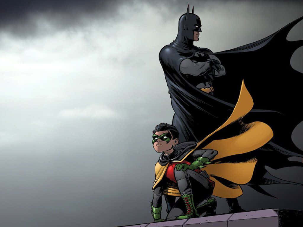 Batman Vs Robin 桌布 壁紙 — 蝙蝠俠和羅賓站在屋頂上，天空灰暗風暴來襲，蝙蝠俠的披風在他們身後飄揚。