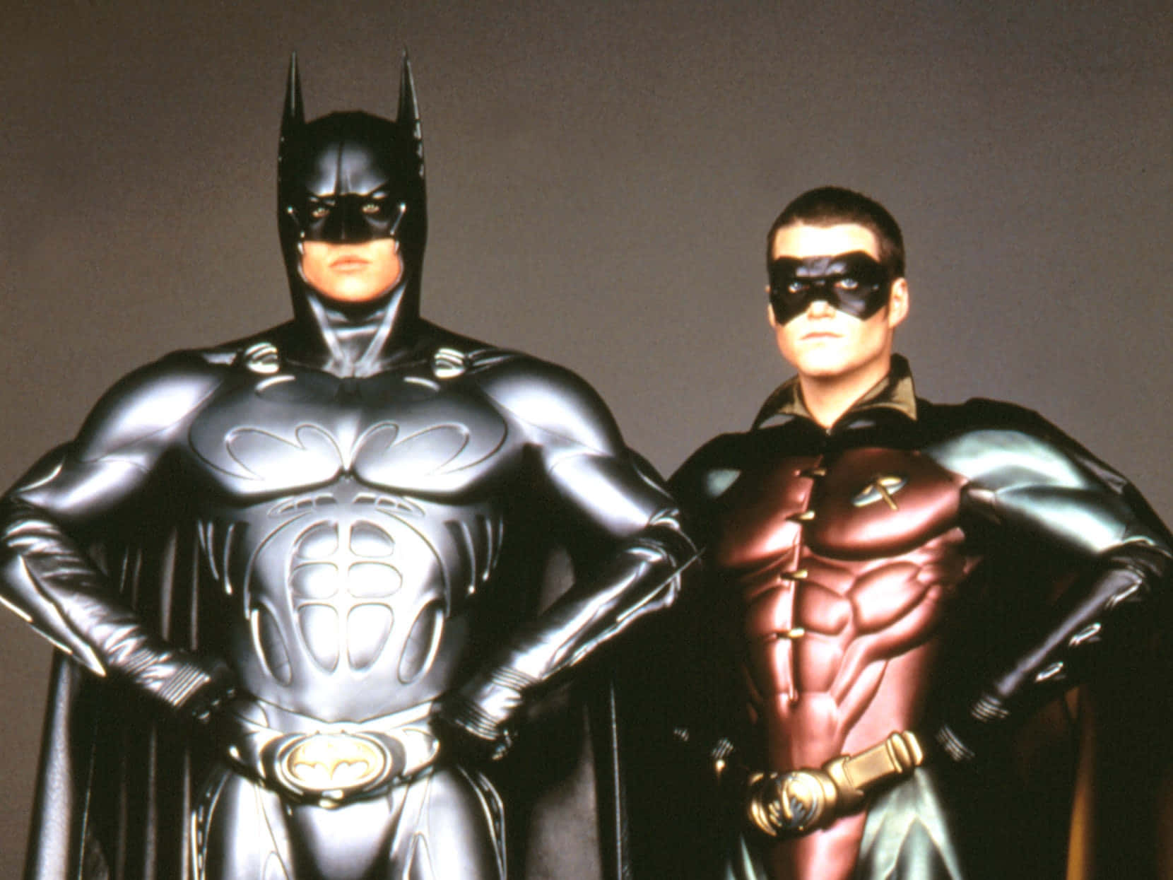 Batman And Robin 桌布 壁紙 — 蝙蝠俠和羅賓自信地穿著他們的標誌性服裝，站在純灰色背景前。
