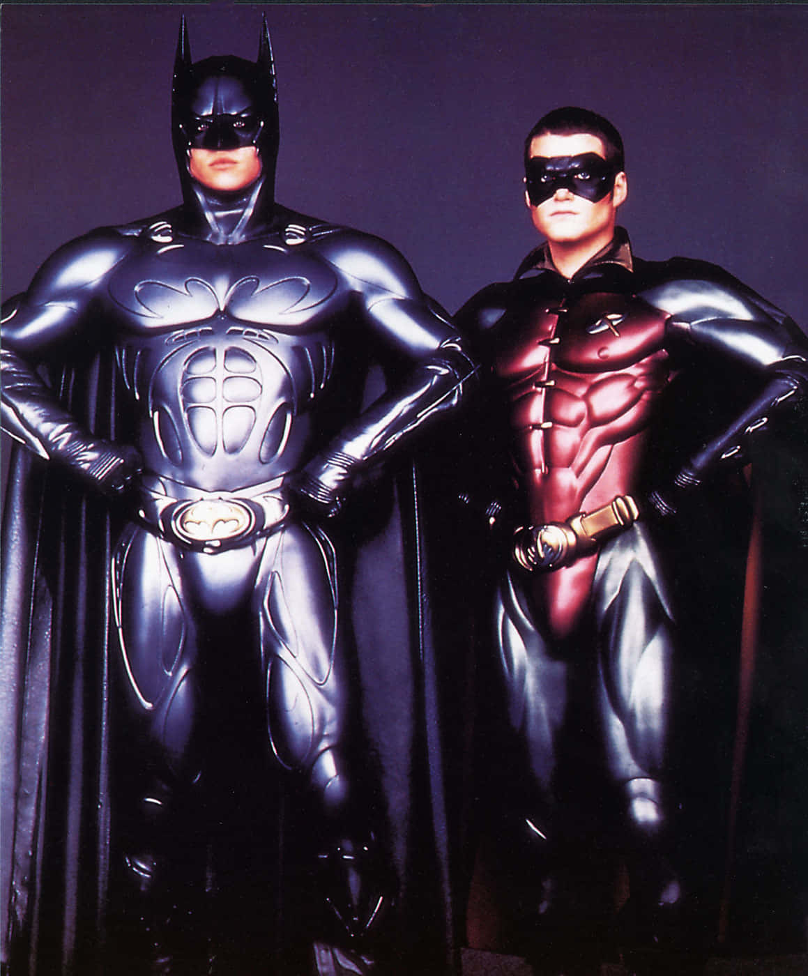 Batman And Robin 桌布 壁紙 — 蝙蝠俠和羅賓自信地穿著閃亮的裝甲服，站在深紫色背景前。