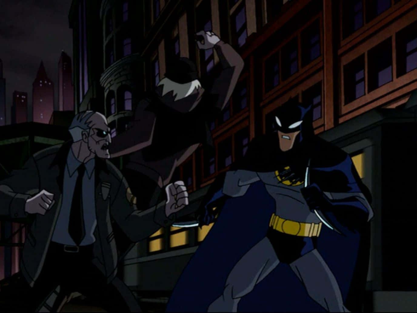 The Batman Vs Dracula 桌布 壁紙 — 蝙蝠俠在夜晚的城市屋頂上，在閃爍的建築燈光下，與一個戴面具的惡棍和一個驚恐萬分的男人對峙。