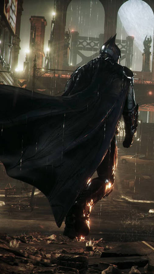 batman arkham city iPhone 桌布 壁紙 — 蝙蝠俠在夜晚站在被雨水浸濕的高譚市小巷中，他的斗篷飄揚，霓虹燈光在濕漉漉的路面上反射。