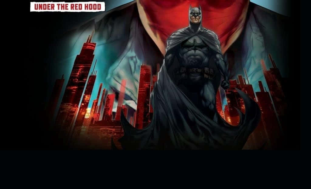 Batman Under The Red Hood 桌布 壁紙 — 蝙蝠俠在戲劇性的天空下，身後是紅色發光的摩天大樓，挑釁地站在黑暗的城市景觀中。