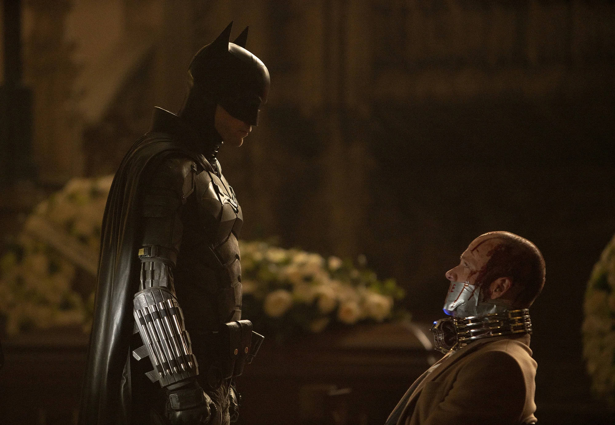 The Batman 2022 桌布 壁紙 — 蝙蝠俠在昏暗的大教堂中聳立，一個戴著機械頸環的面具男跪在他面前。