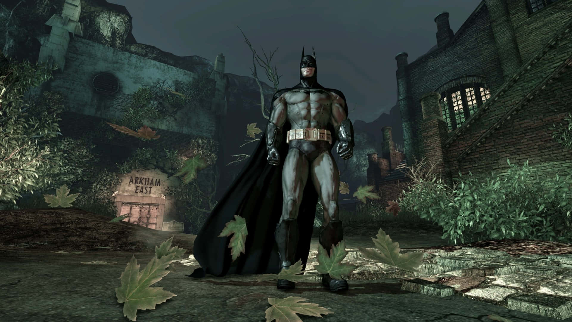 Arkham Asylum 桌布 壁紙 — 蝙蝠俠在陰沉天空下，威嚴地站在破敗、雜草叢生的阿卡漢精神病院庭院中。