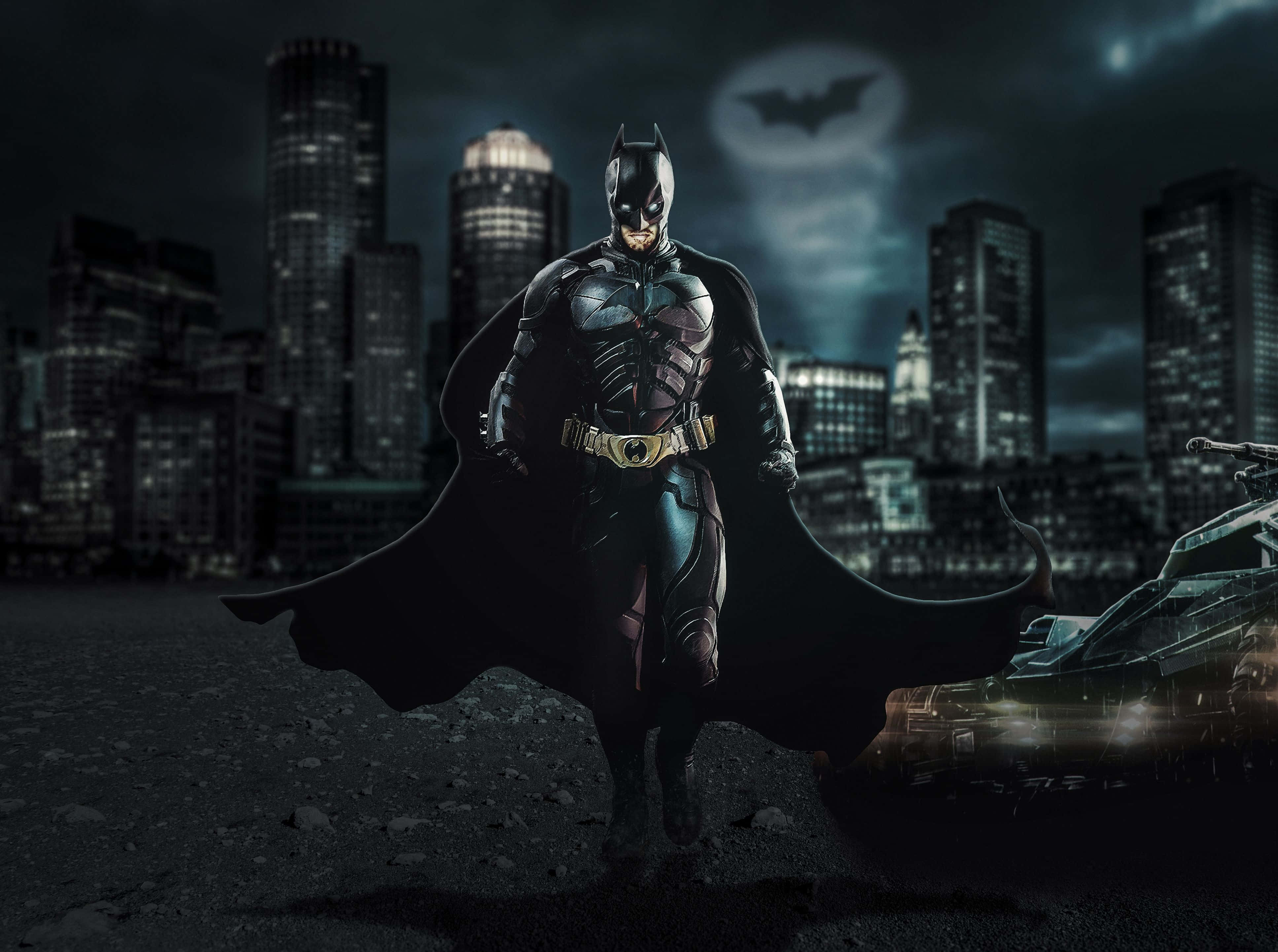 4K Batmobile 桌布 壁紙 — 蝙蝠俠在雨中的高譚市夜景中英勇站立，披風飄揚，蝙蝠信號在天空中閃耀。
