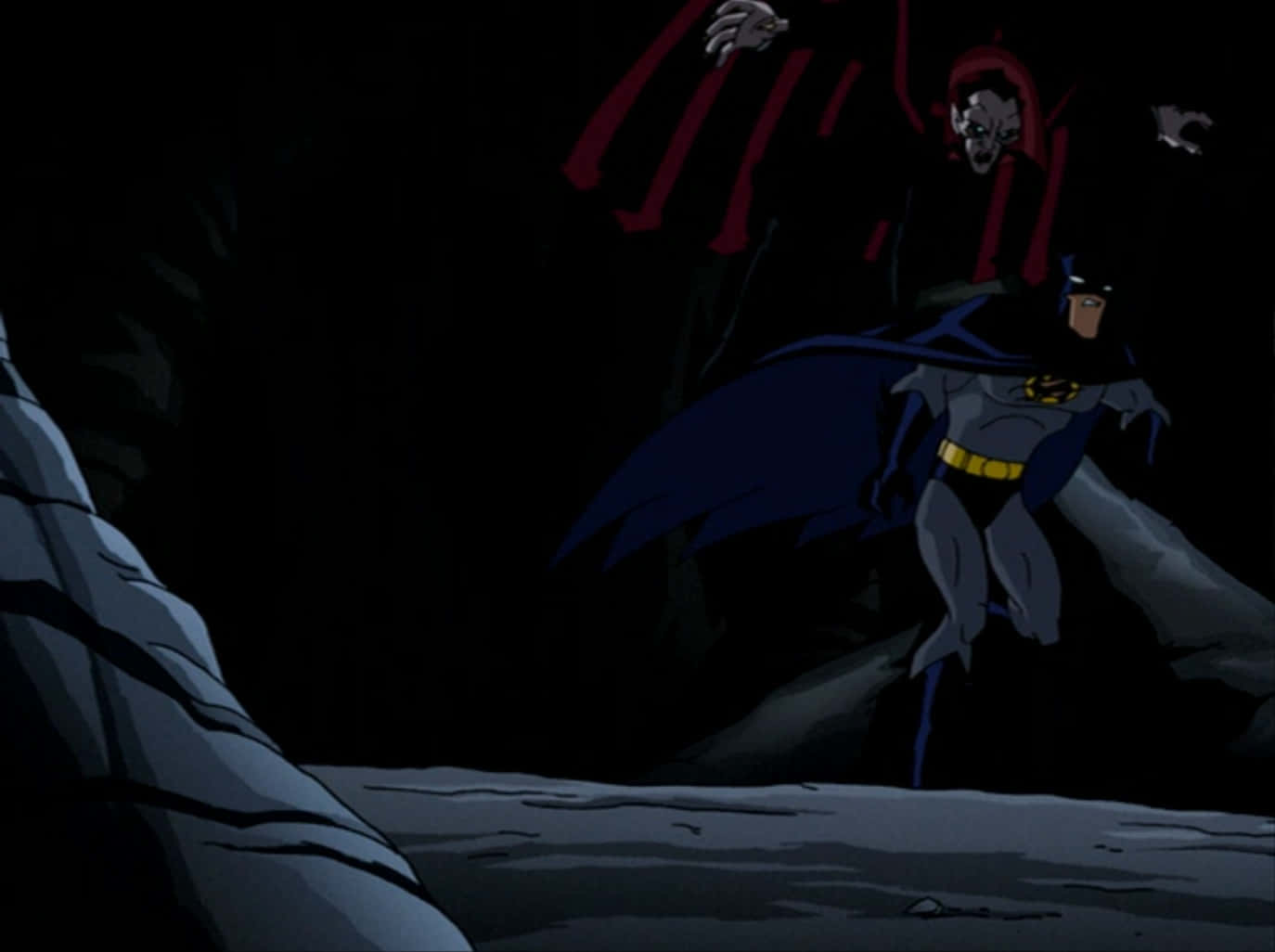 The Batman Vs Dracula 桌布 壁紙 — 蝙蝠俠在黑暗洞穴中挑釁地站立，身後一個身穿紅袍的威脅人物赫然聳立。