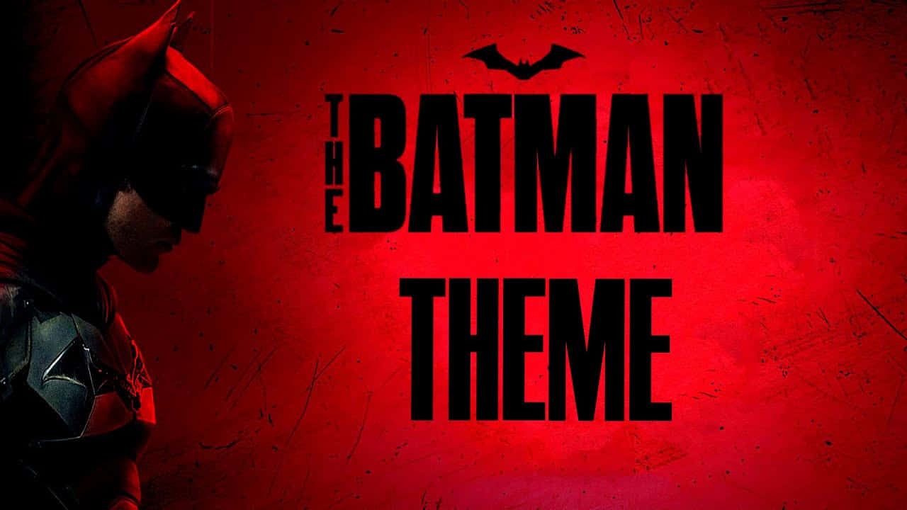 Batman Year One 桌布 壁紙 — 蝙蝠俠戴著深色頭罩，站在陰影中，背景是粗糙的紅牆，上面有粗體黑色文字寫著「THE BATMAN THEME」和蝙蝠標誌。