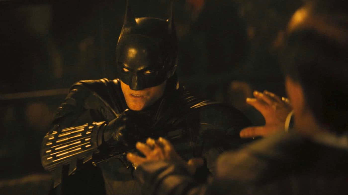 Bruce Wayne 桌布 壁紙 — 蝙蝠俠戴著深色頭罩和裝甲手套，在昏暗的城市小巷中以緊張的肢體語言對峙對手。