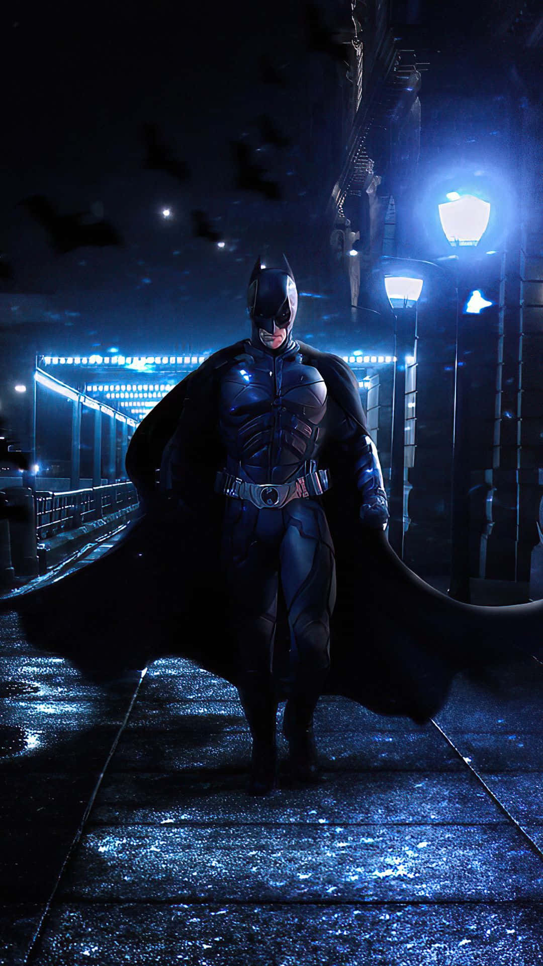 Batman City 桌布 壁紙 — 蝙蝠俠獨自站在夜晚被雨水打濕的橋上，頭頂有蝙蝠飛過，下方是發光的街燈。