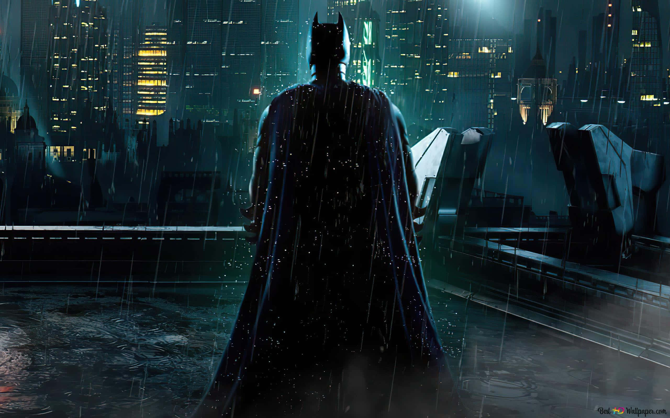 Batman City 桌布 壁紙 — 蝙蝠俠獨自站在被雨水浸濕的屋頂上，俯瞰夜晚霓虹燈閃爍的高譚市景觀。