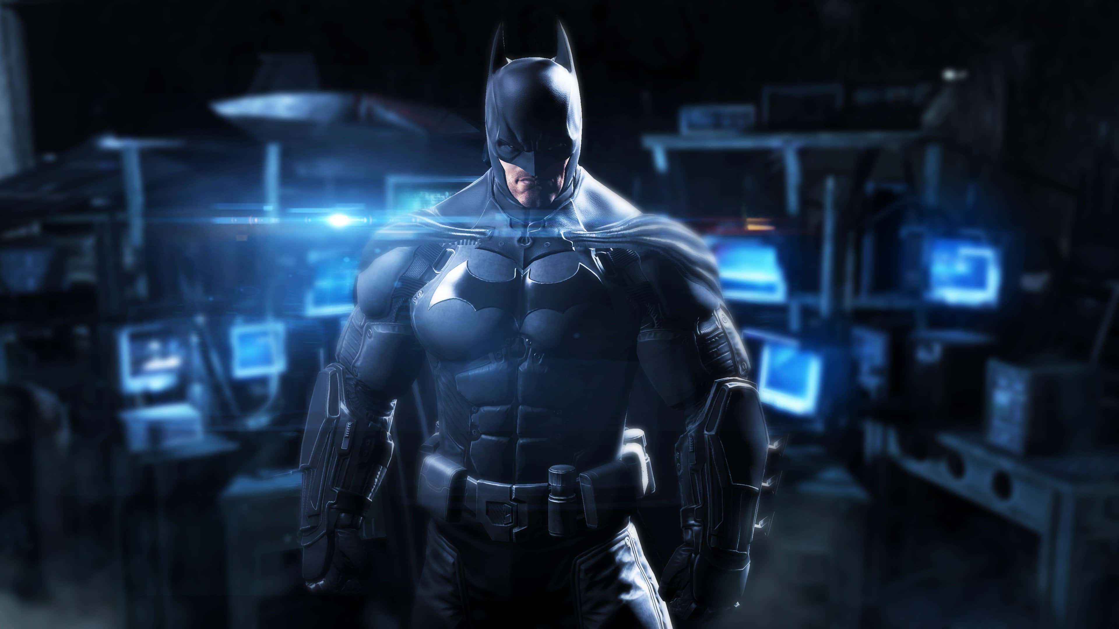 Batman Arkham Origins 桌布 壁紙 — 蝙蝠俠站在一個光線昏暗、充滿科技感的房間裡，藍色發光螢幕將光線投射在他的裝甲服上。