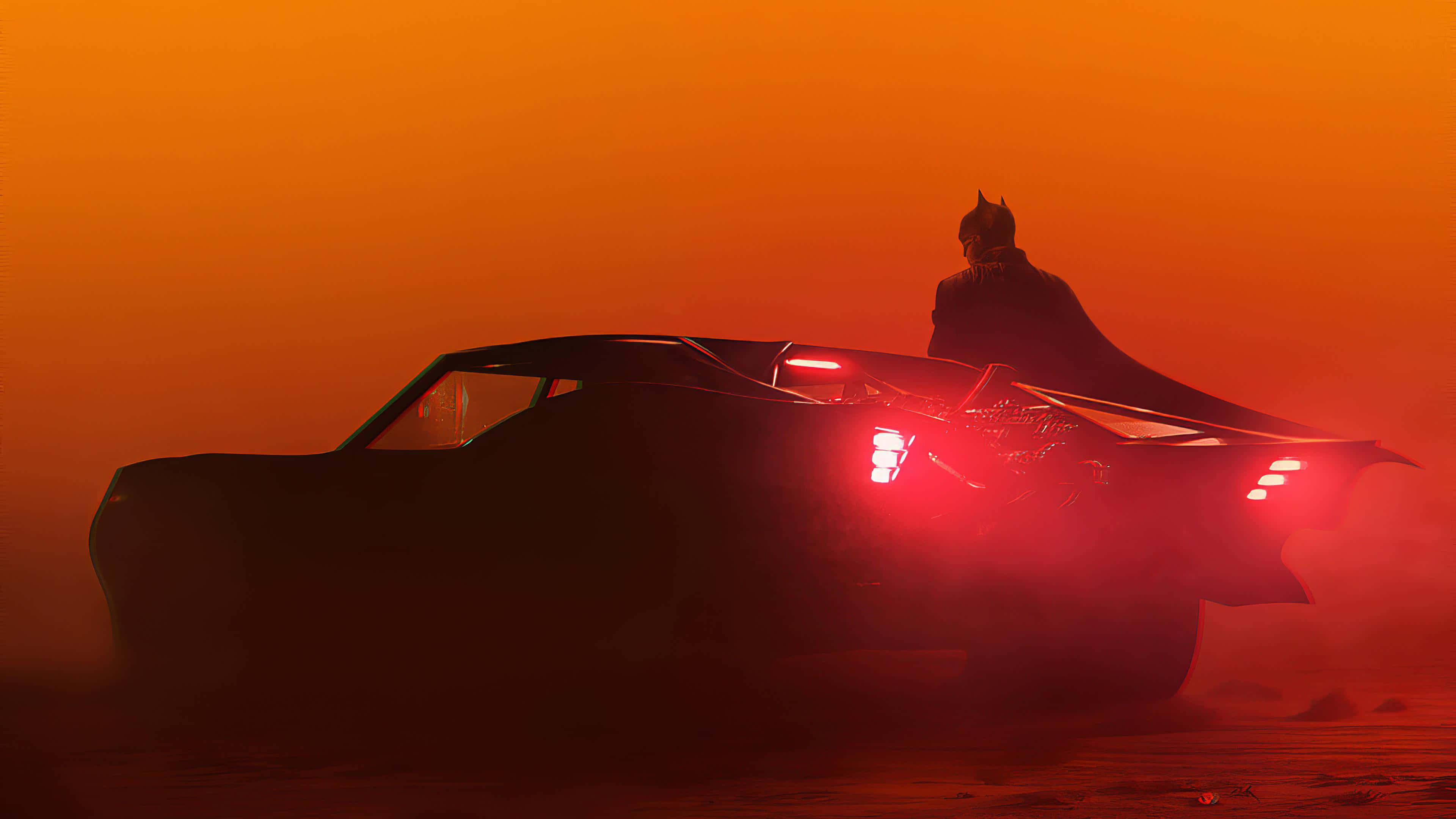 Batmobile Desktop 桌布 壁紙 — 蝙蝠俠站在他的蝙蝠車頂上，紅色尾燈閃爍，穿透朦朧的橙色沙漠黃昏。