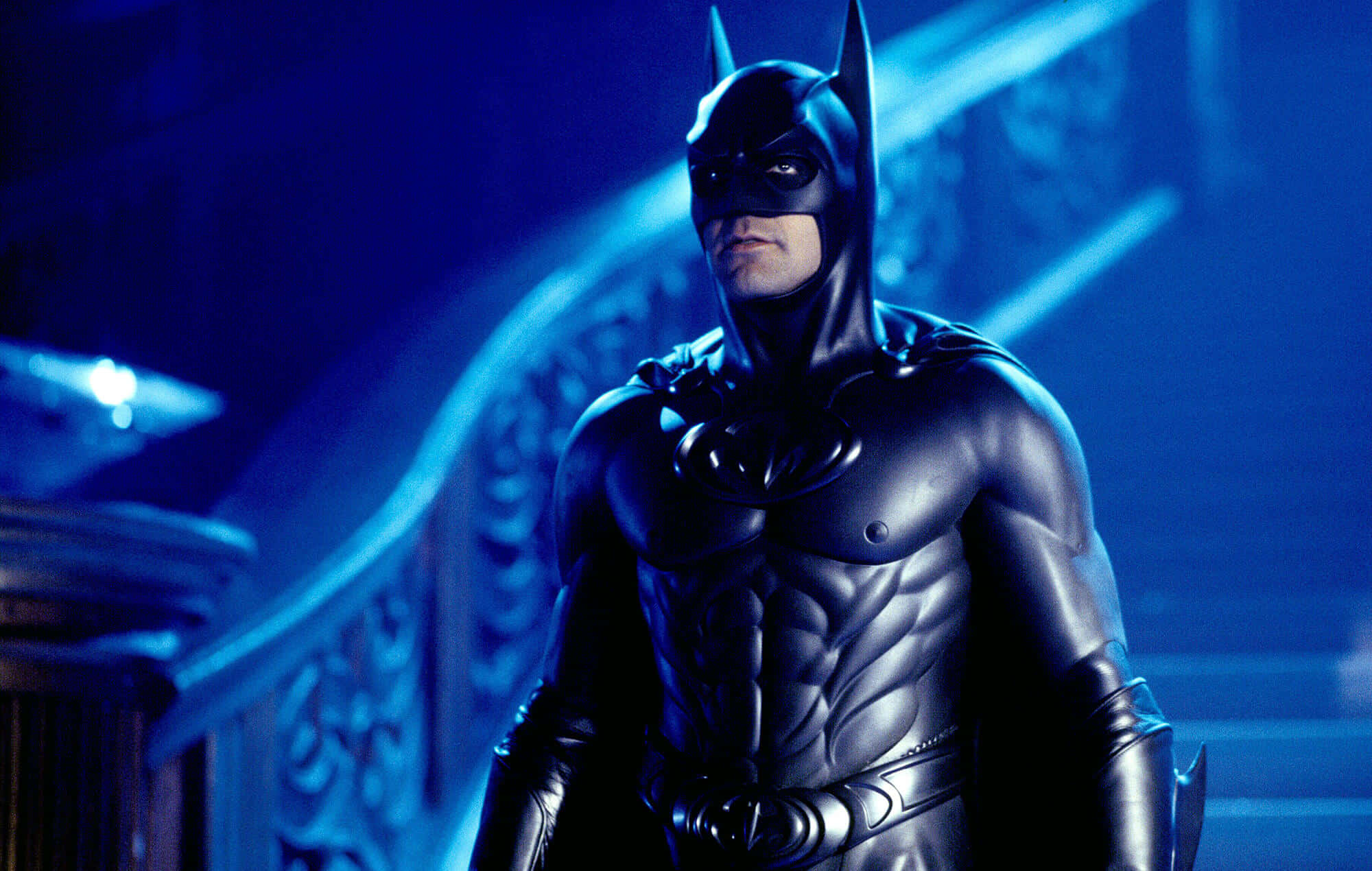 Bat-suit 桌布 壁紙 — 蝙蝠俠站在昏暗的哥德式走廊中，沐浴在冷藍色光線下，戲劇性的陰影凸顯了他的裝甲服。
