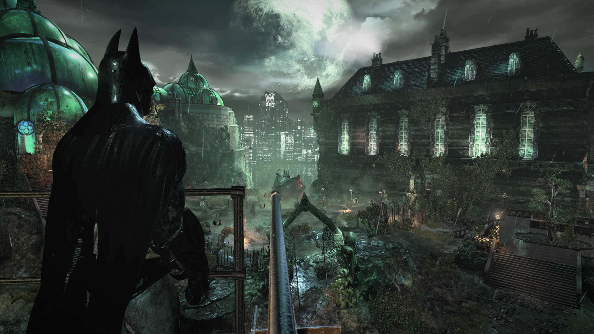 Arkham Asylum 桌布 壁紙 — 蝙蝠俠站在濕滑的屋頂上，俯瞰滿月下的哥德式城市景觀，下方有發光的窗戶和霧氣瀰漫的街道。