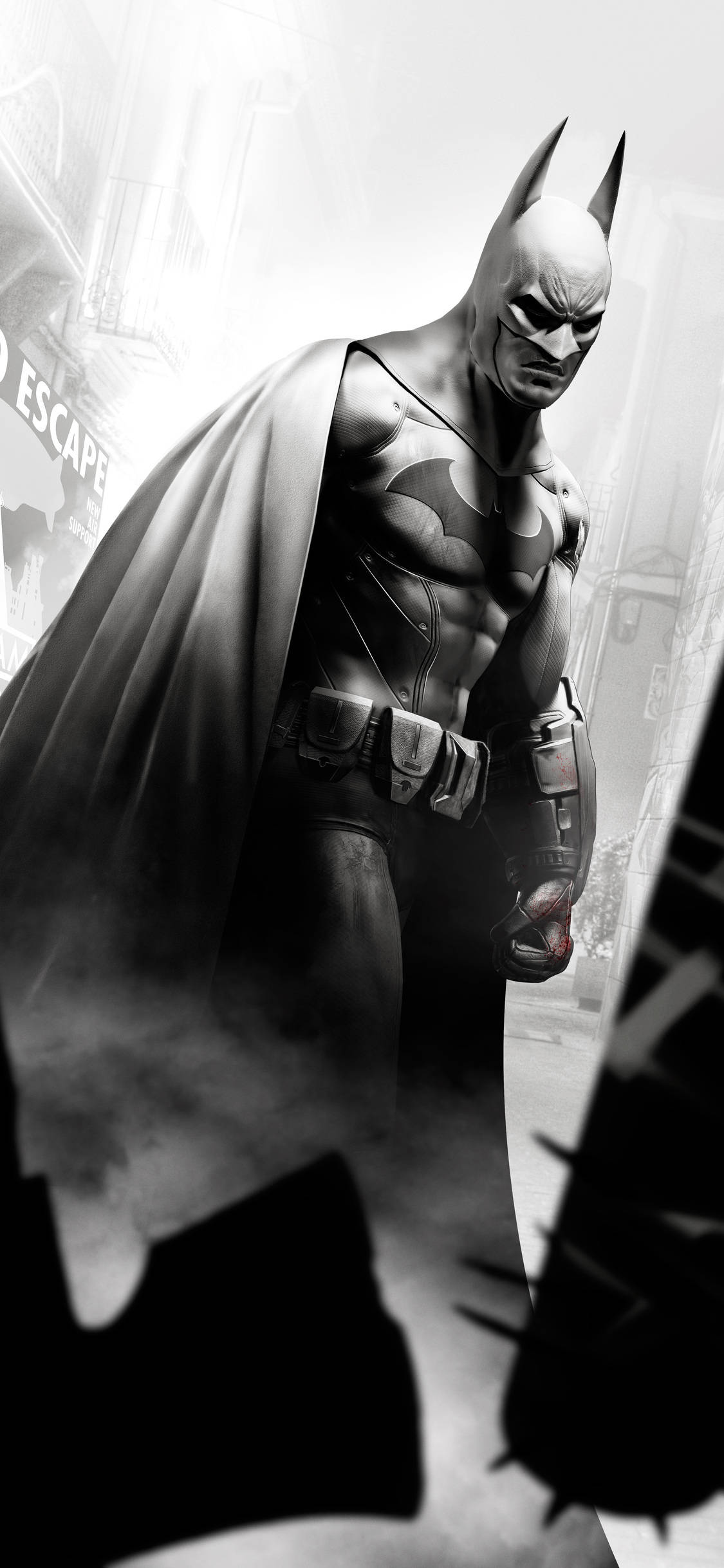 Arkham 桌布 壁紙 — 蝙蝠俠站在灰暗單色的城市景觀中，斗篷飄揚，表情嚴肅，周圍是城市衰敗和迷霧。