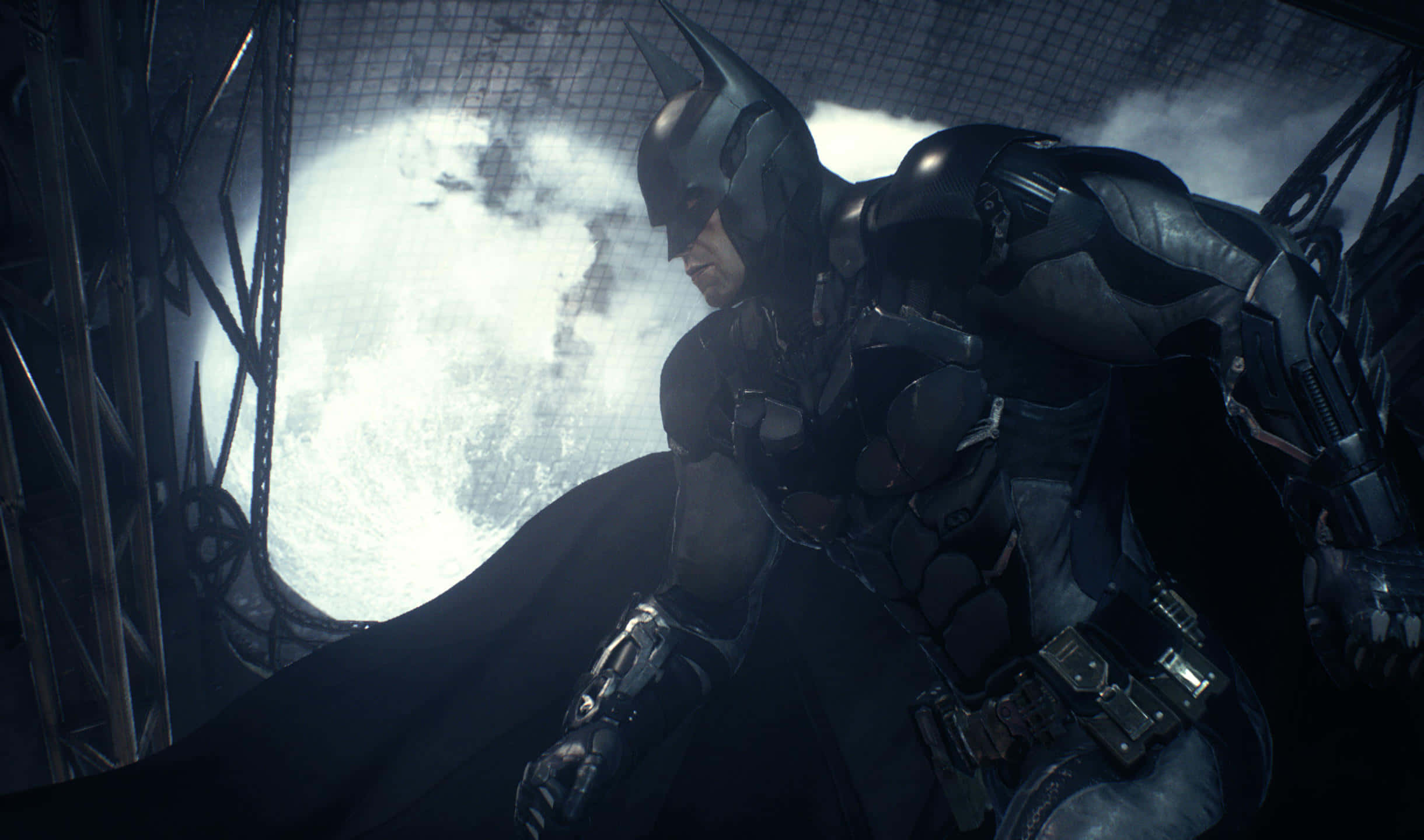 2440x1440 Batman Arkham City 桌布 壁紙 — 蝙蝠俠蹲在黑暗的工業環境中，一輪明亮的滿月透過鐵窗在他身後發光。