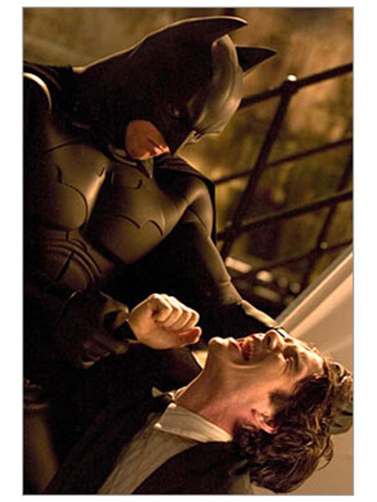 Batman Begins 桌布 壁紙 — 蝙蝠俠身穿深色西裝，在緊張昏暗的對峙中籠罩著一名尖叫的男子。
