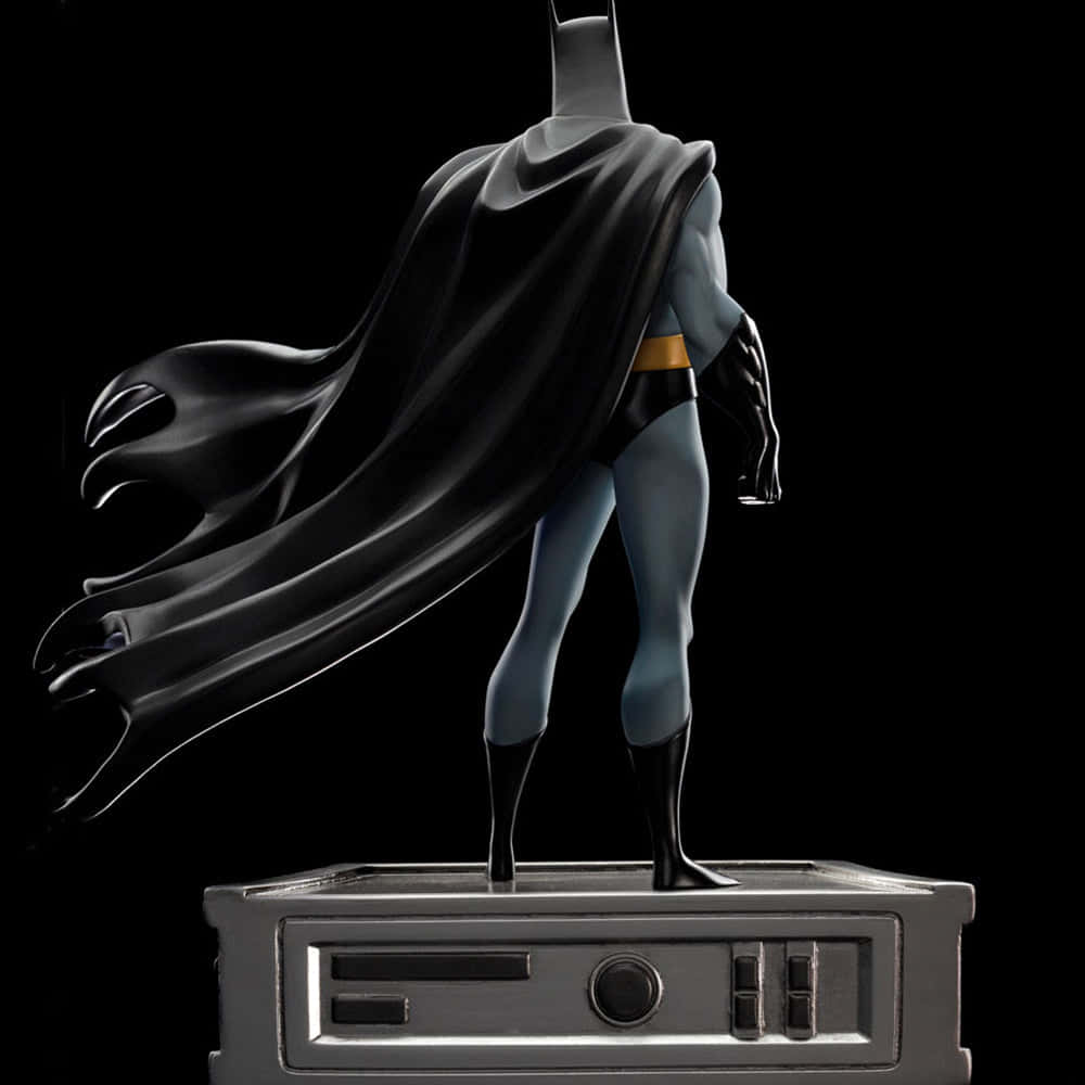 Batman Animated Adventures 桌布 壁紙 — 蝙蝠俠雕像矗立在復古收音機底座上，披風在純黑背景下戲劇性地飄揚。