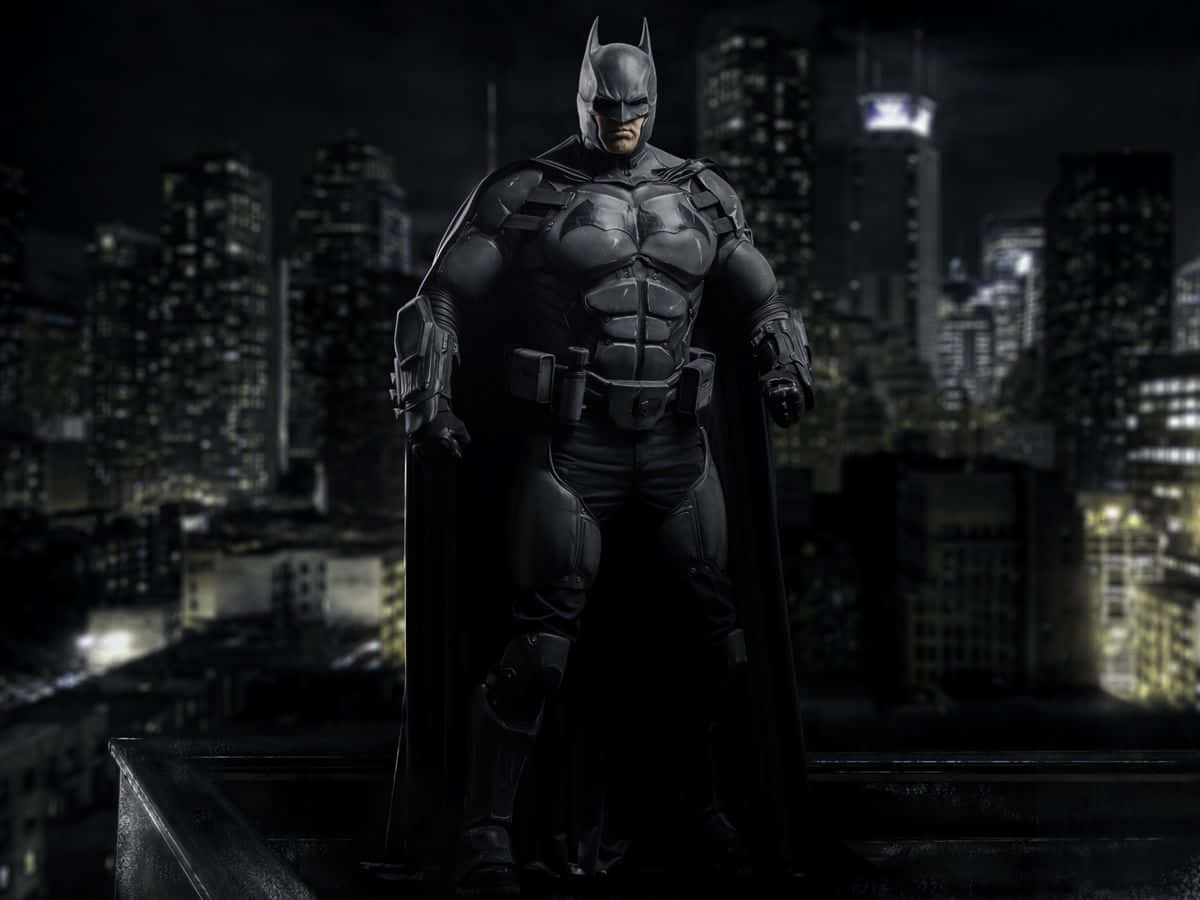 Bat-suit 桌布 壁紙 — 蝙蝠俠高高站在屋頂上，俯瞰夜晚黑暗而燈火通明的城市景觀，目光堅定。