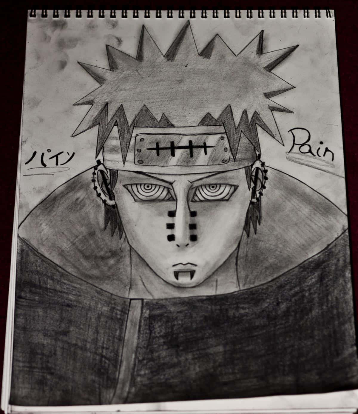 Akatsuki Drawing 桌布 壁紙 — 螺旋筆記本頁面上動漫角色佩恩（Pain）的詳細鉛筆素描，帶有尖刺頭髮和額頭護具。