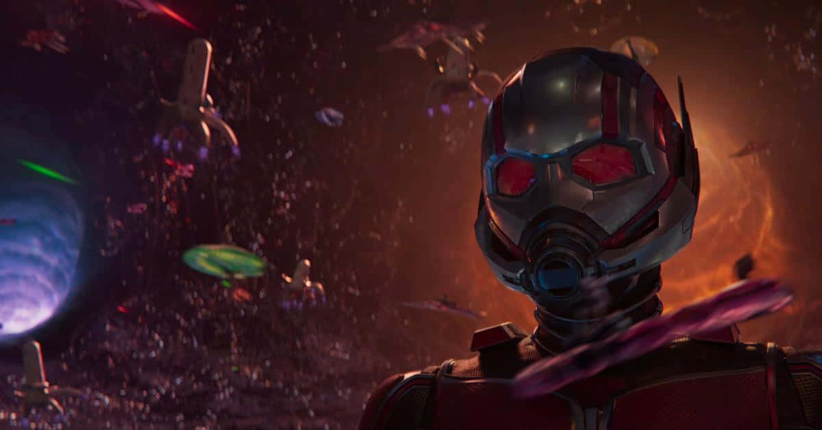 Quantum Realm 桌布 壁紙 — 蟻人穿著戰衣站在宇宙碎片中，背景有發光的行星和漂浮的太空船。