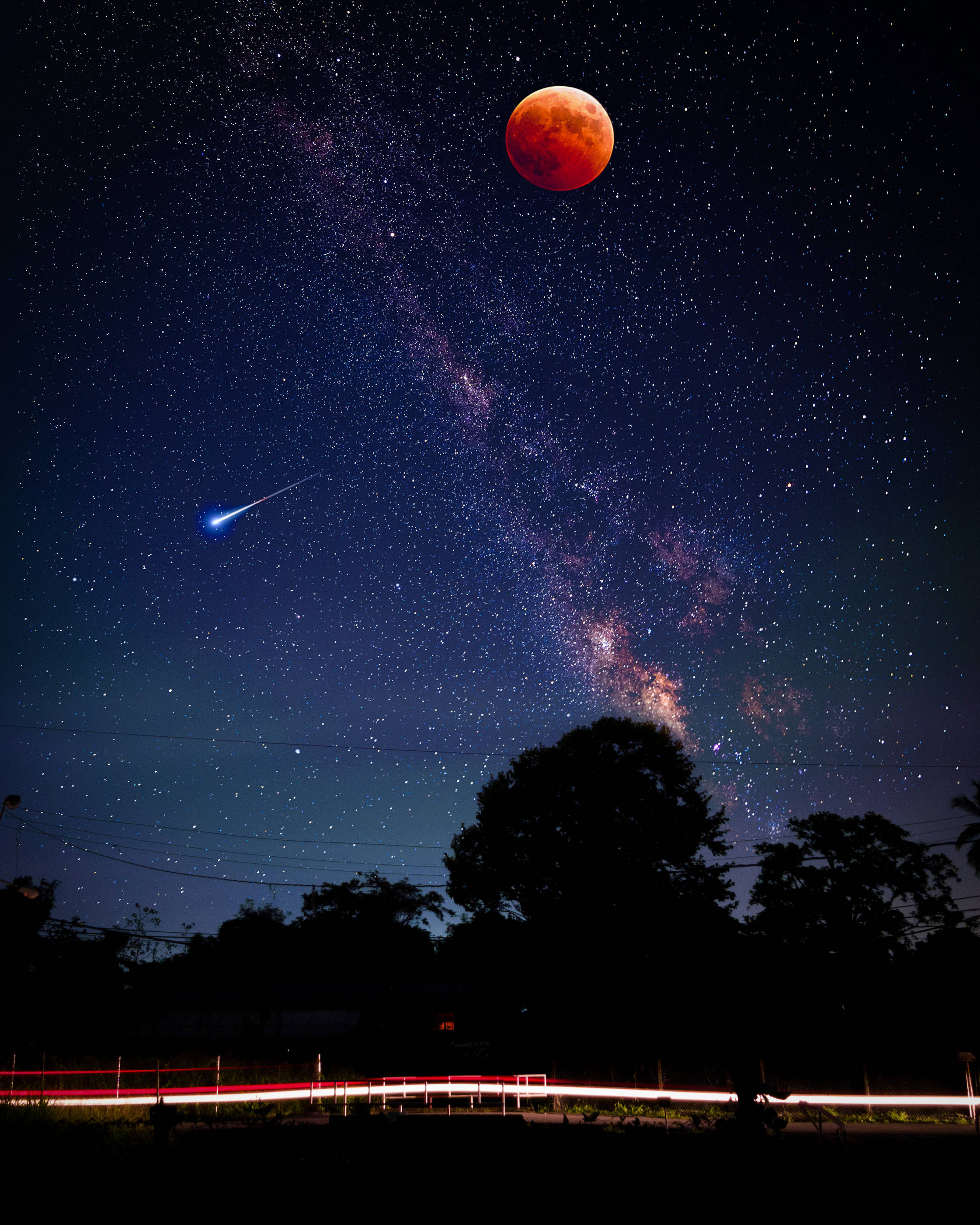 太空 桌布 壁紙 — 血月在滿天星斗的夜空中發出紅光，一顆明亮的流星劃過銀河，掠過剪影樹木和光跡。