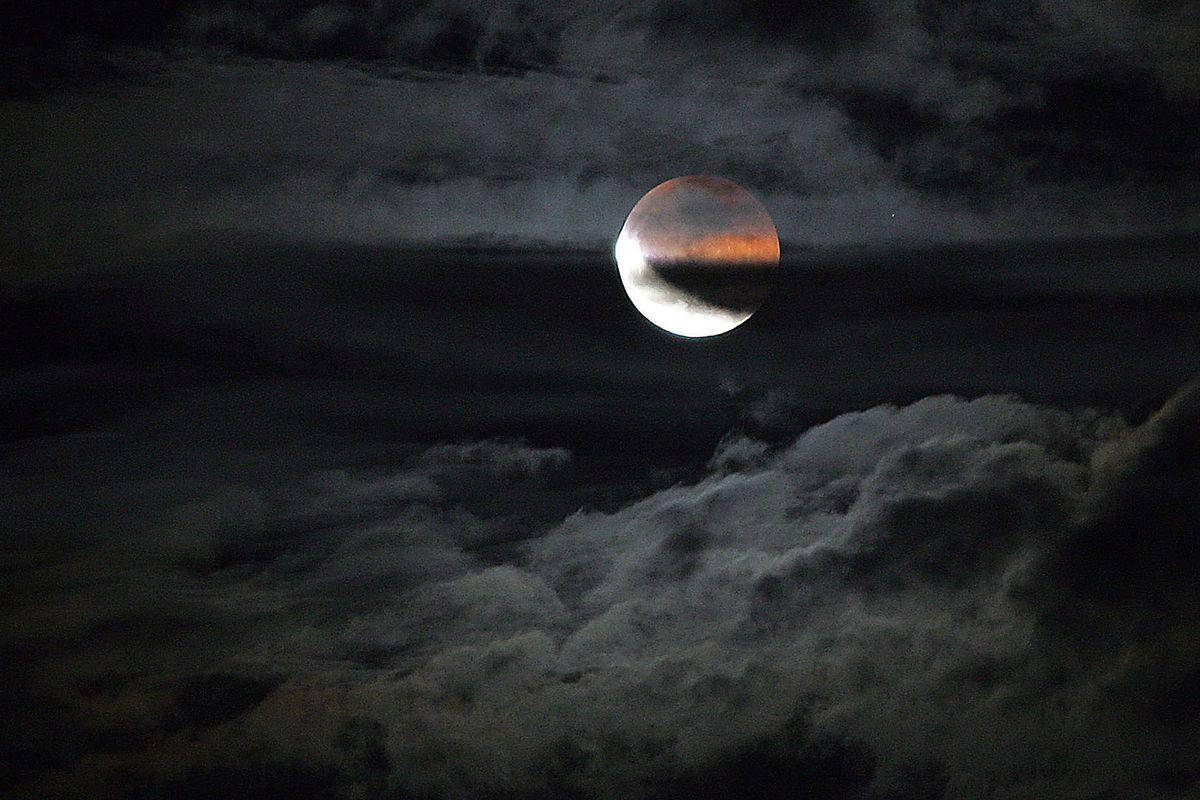 Eclipse 桌布 壁紙 — 血月在黑暗雲層中發光，伴隨著旋轉的灰色和黑色雲層，構成戲劇性的夜空。