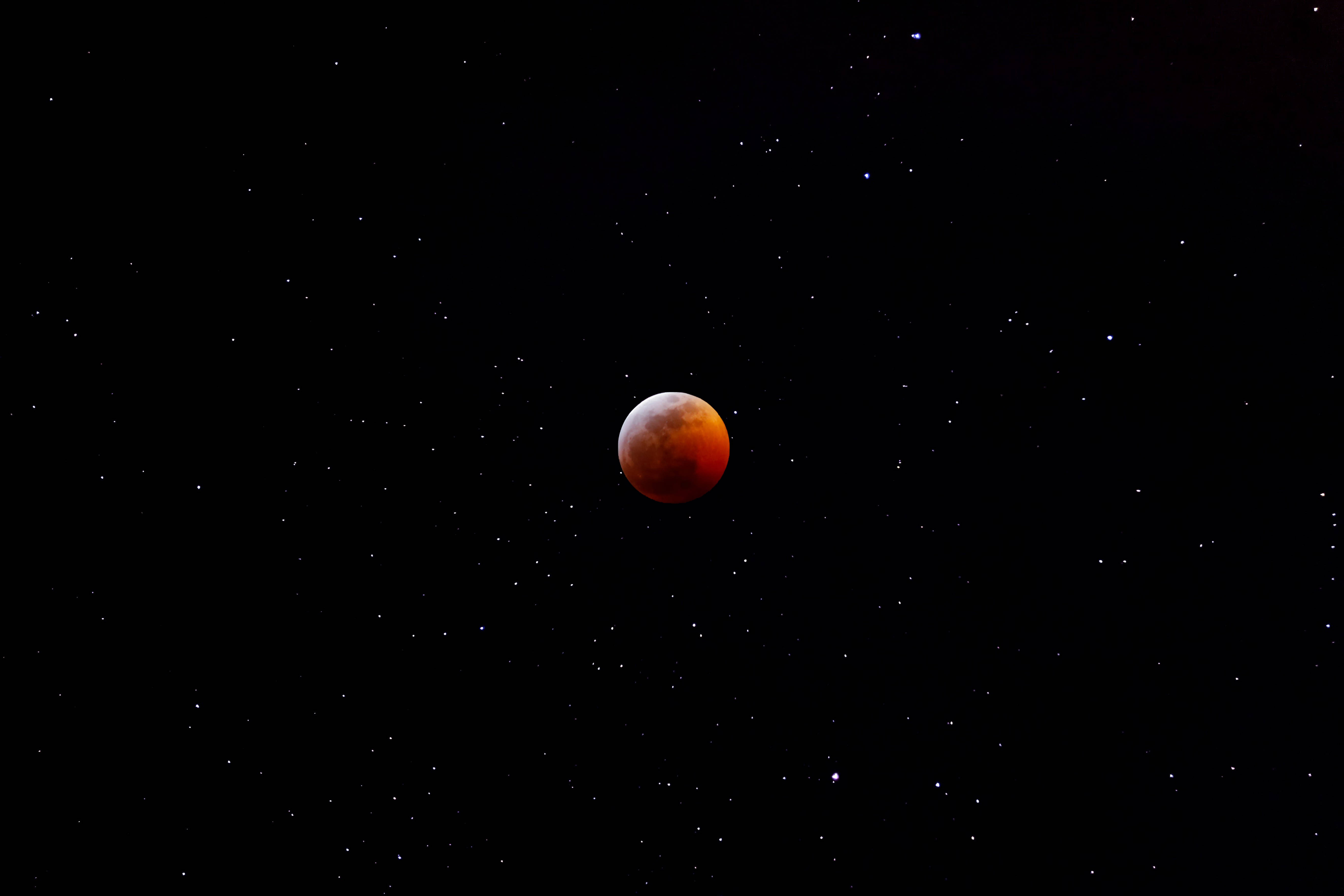 Blood 桌布 壁紙 — 血月發出琥珀色光芒，映襯著繁星點點的夜空，散落著點點星光。