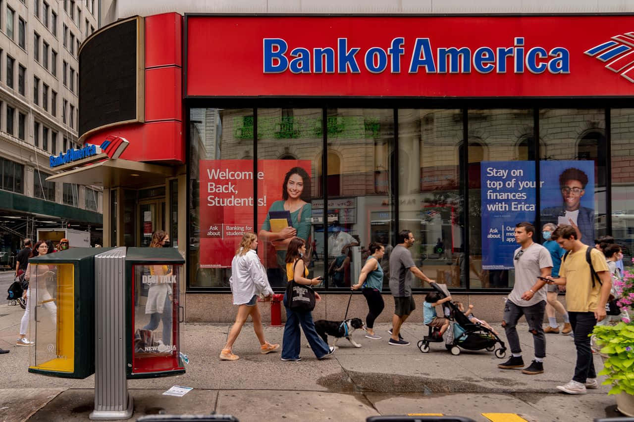 Bank Of America 桌布 壁紙 — 行人經過一間美國銀行分行，該分行設有紅色招牌和玻璃窗，展示學生銀行服務廣告。
