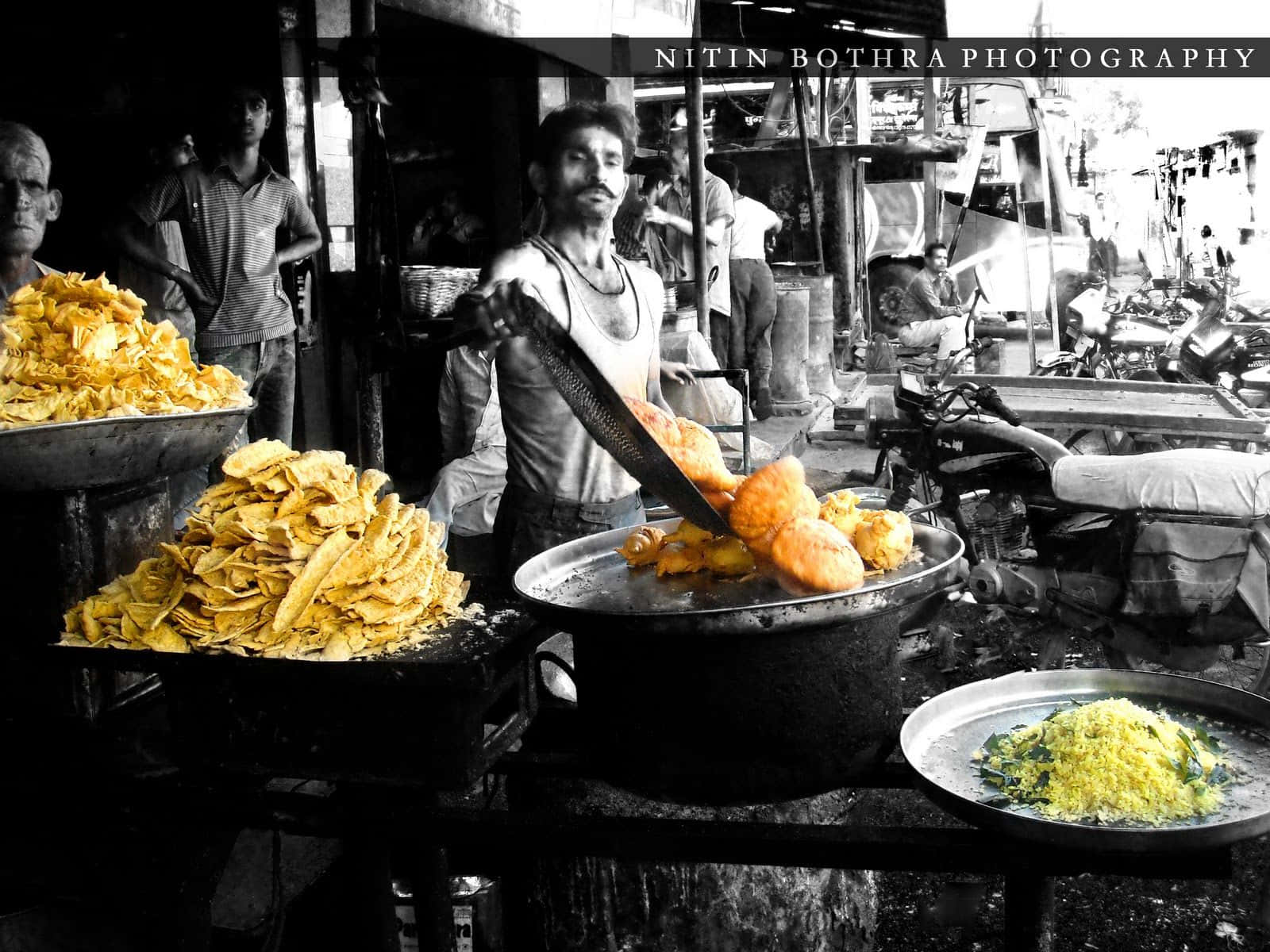Indian 桌布 壁紙 — 街頭小販在熱鬧的市場活動中，熟練地翻動煎鍋中的金黃色炸物。