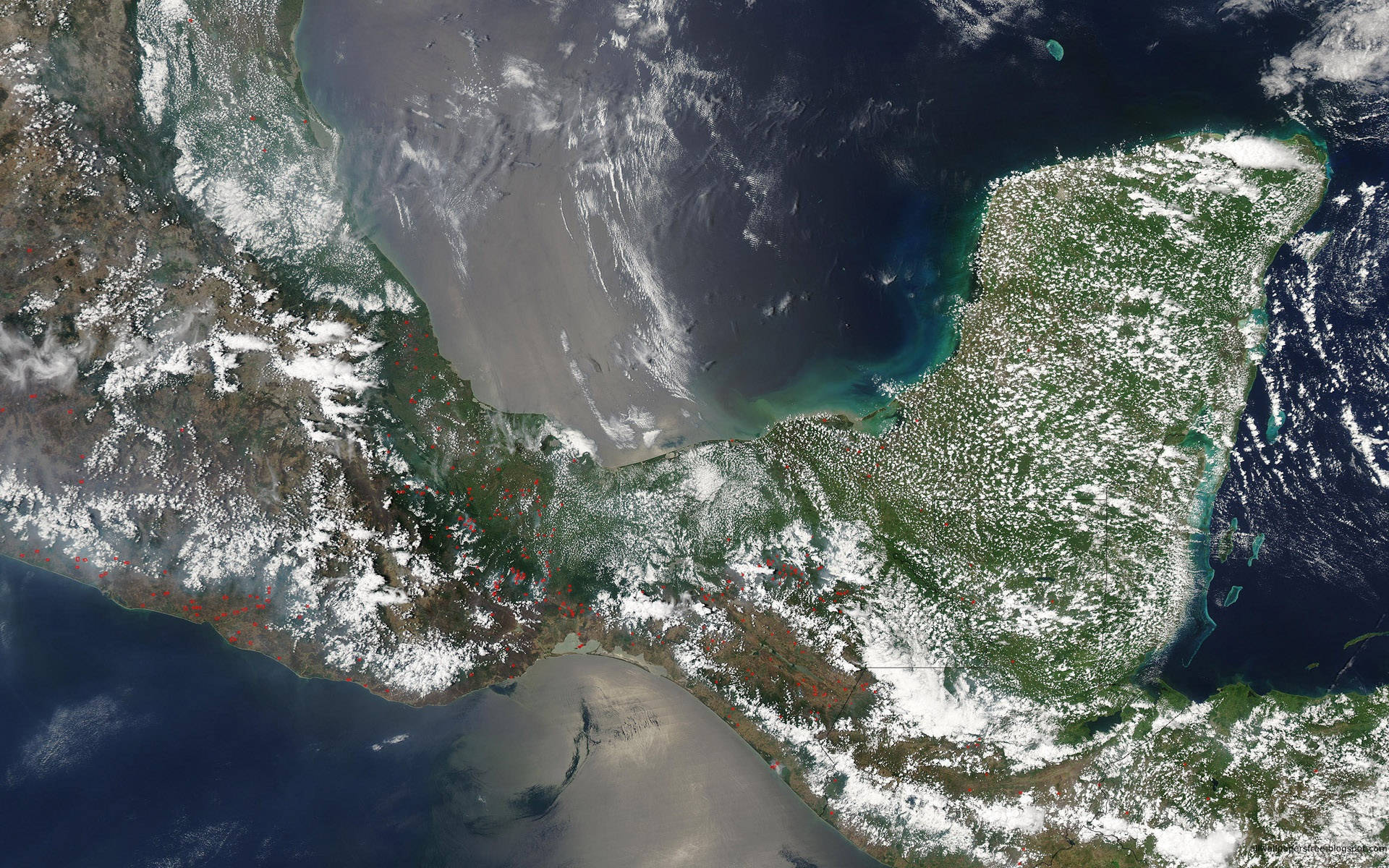 Guatemala 桌布 壁紙 — 衛星圖像顯示一個被雪覆蓋的半島伸入深藍色海洋，伴有旋轉的雲層和沿海城市。