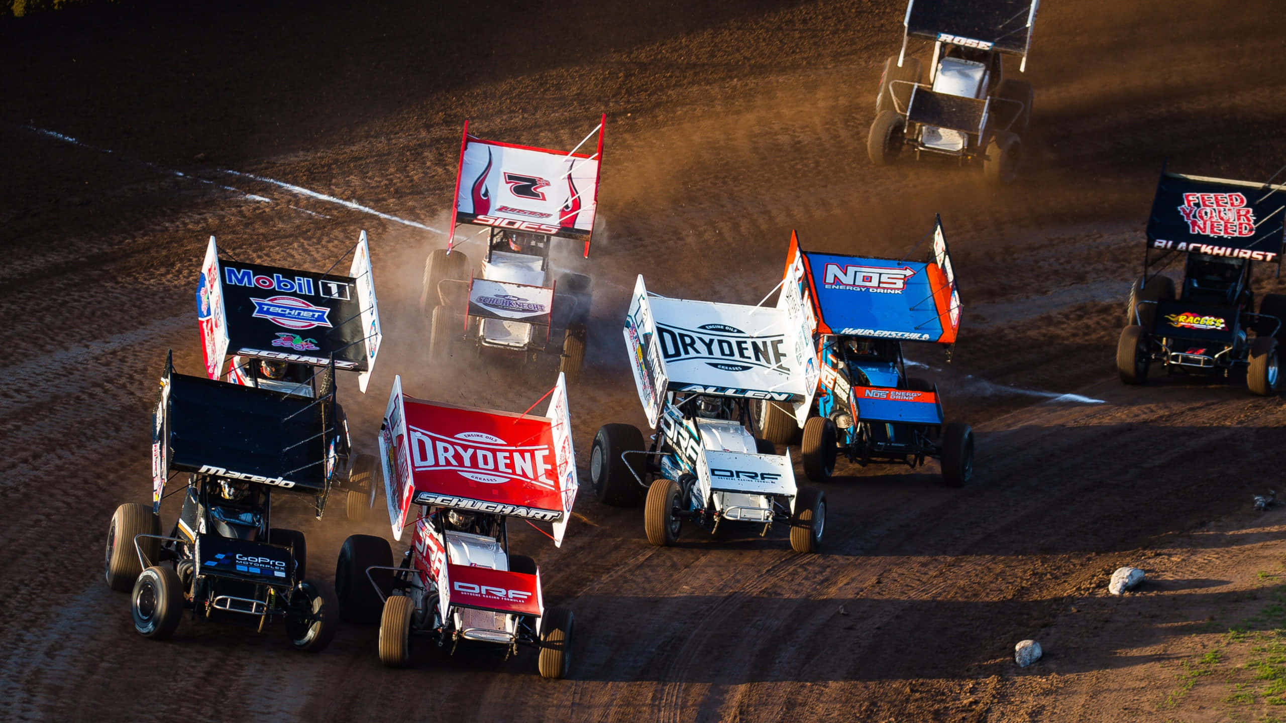 Sprint Car Racing 桌布 壁紙 — 衝刺賽車在泥地賽道上激烈競速，在體育場燈光下揚起滾滾塵土。