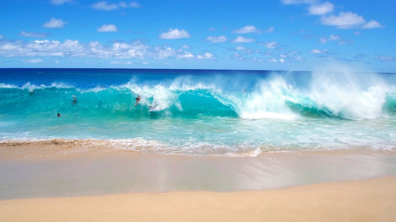 Beach Dual Monitor 桌布 壁紙 — 衝浪者在蔚藍的海浪上滑行，海浪拍打著金色的沙灘，天空湛藍，白雲點綴。
