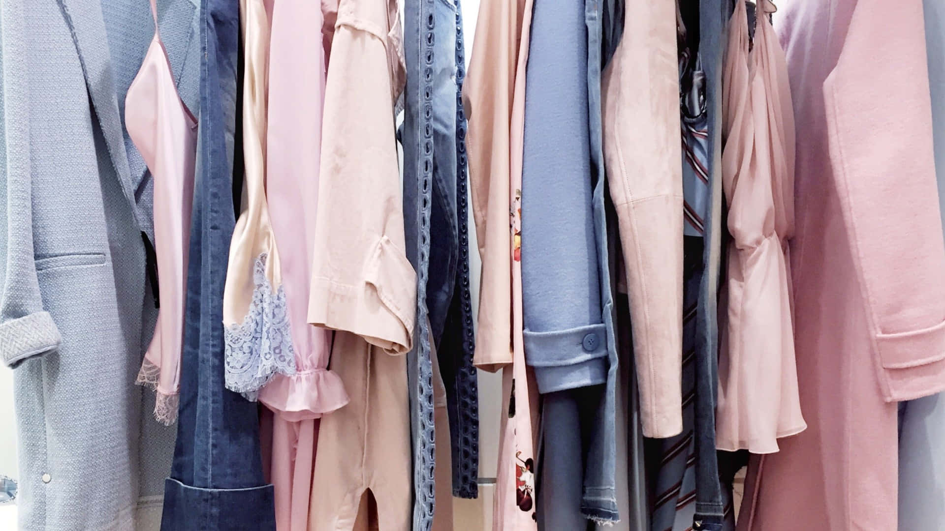 Clothes 桌布 壁紙 — 衣櫃桿上整齊掛著的柔和粉彩和牛仔布色調衣物的特寫。