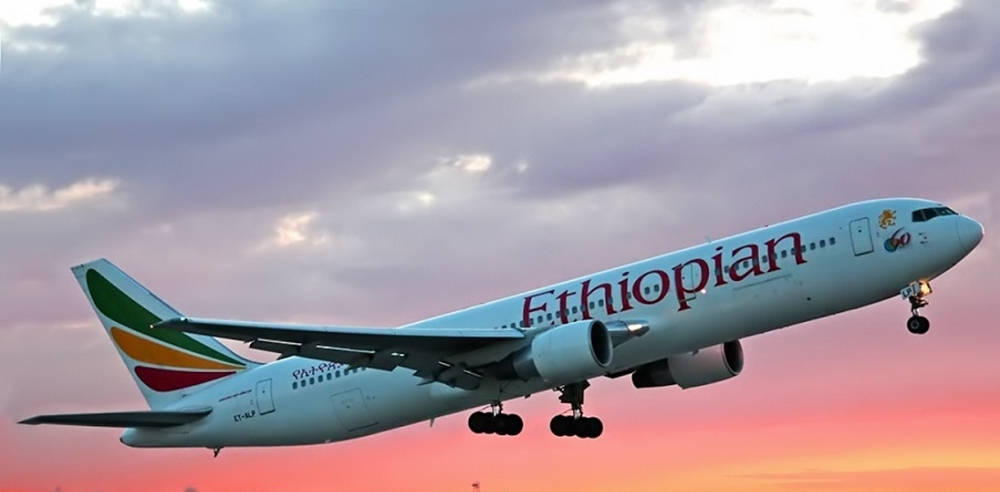  壁紙 — 衣索比亞航空的飛機在充滿活力的粉紅色和紫色日落天空與雲層中下降。