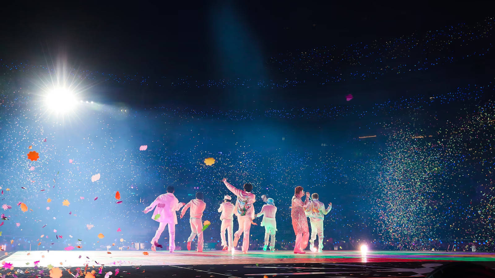 一群表演者在舞台上，在明亮燈光下與飄落的紙屑一同慶祝。 — BTS ARMY GIF 壁紙
