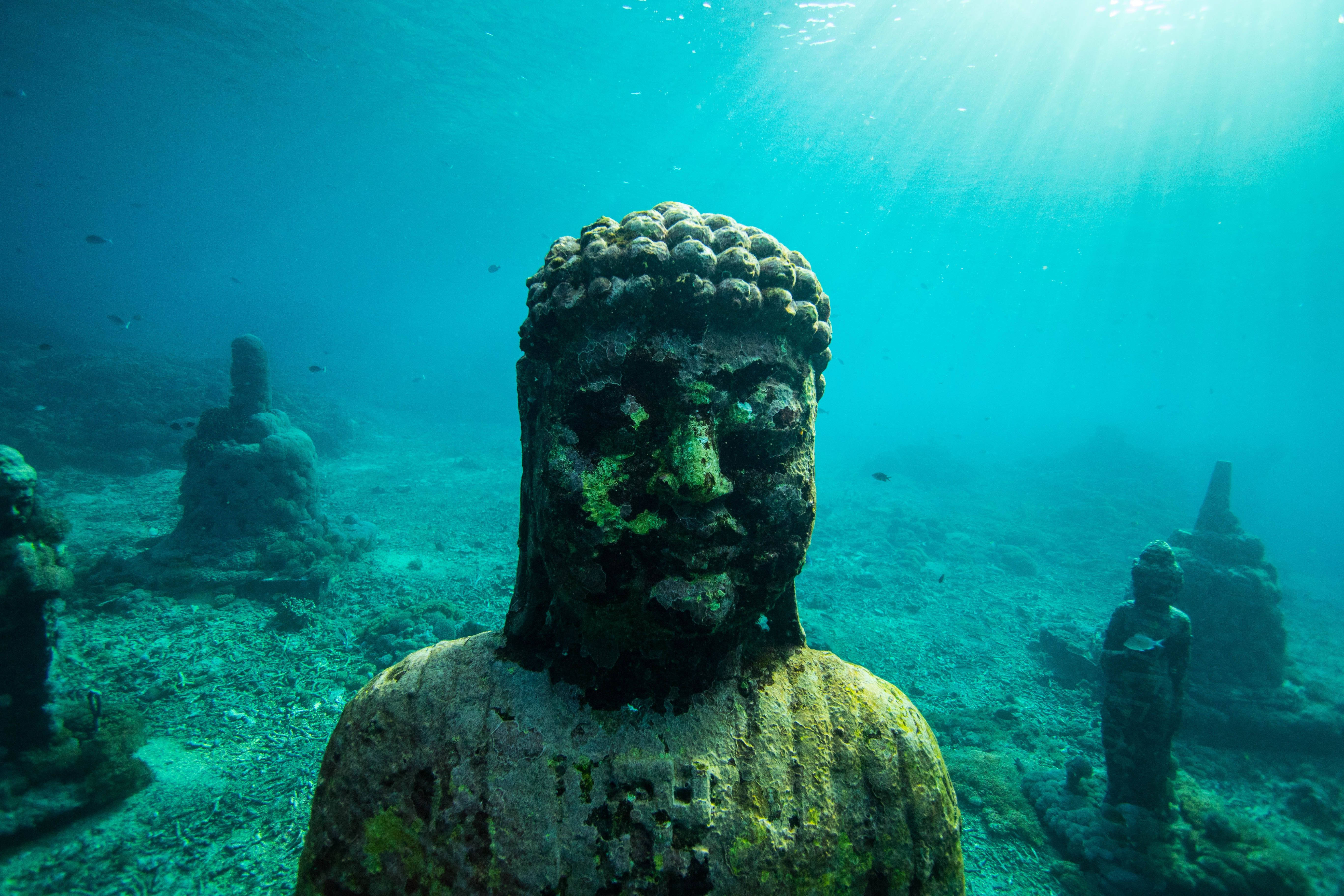 Snorkeling 桌布 壁紙 — 被藻類覆蓋的古老佛像躺在陽光照射的海底，光線穿透碧綠的海水。
