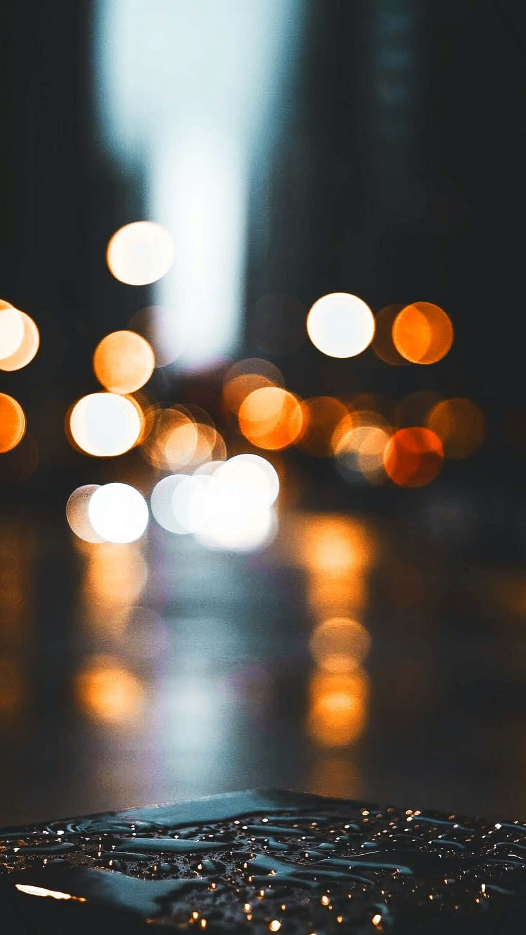 背景 桌布 壁紙 — 被雨水浸濕的路面反射出模糊的城市燈光，營造出憂鬱的夜間城市場景。