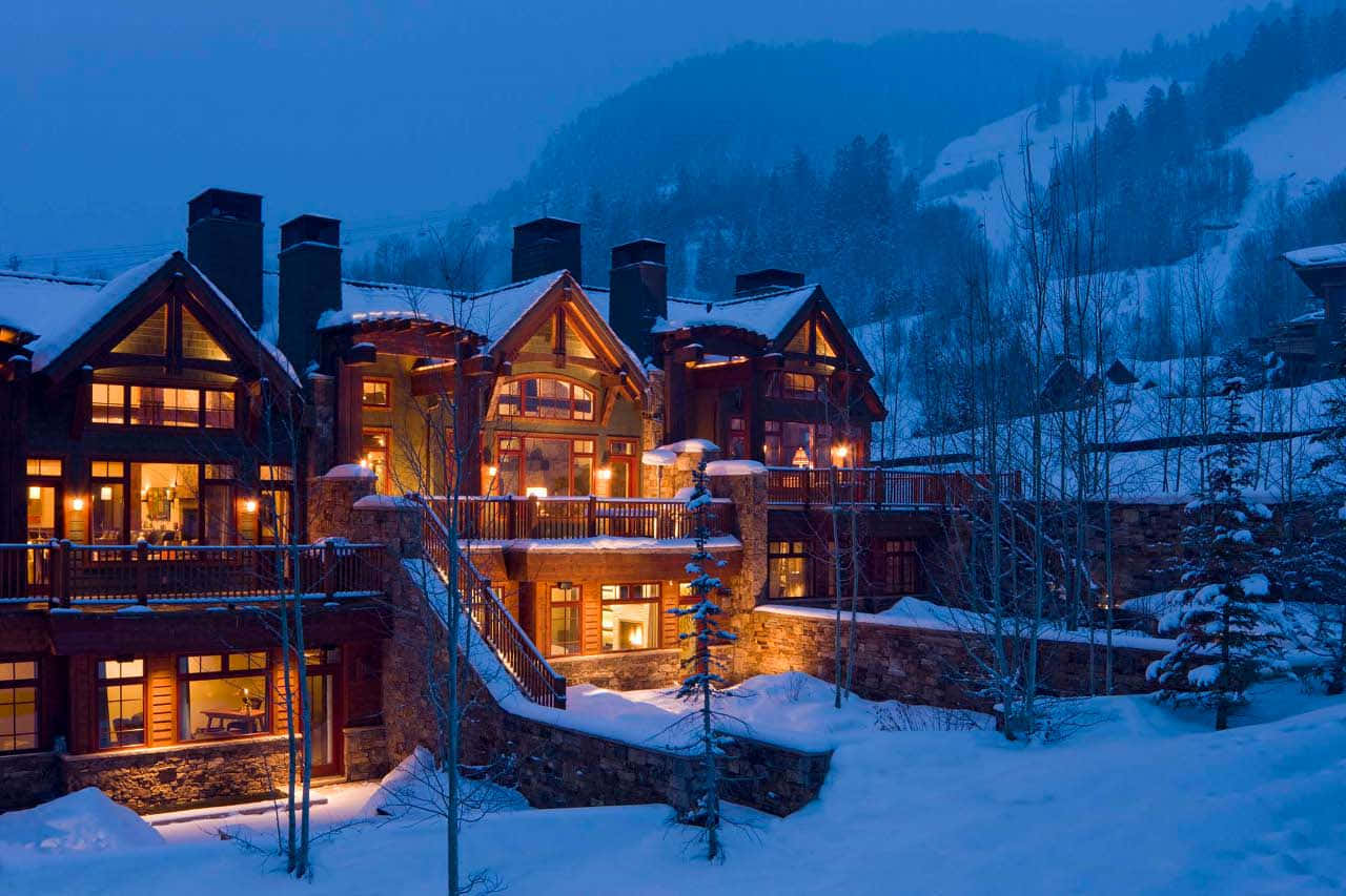Aspen Colorado 桌布 壁紙 — 被雪覆蓋的山間小屋，溫暖發光的窗戶，坐落在冬日森林的暮色中。