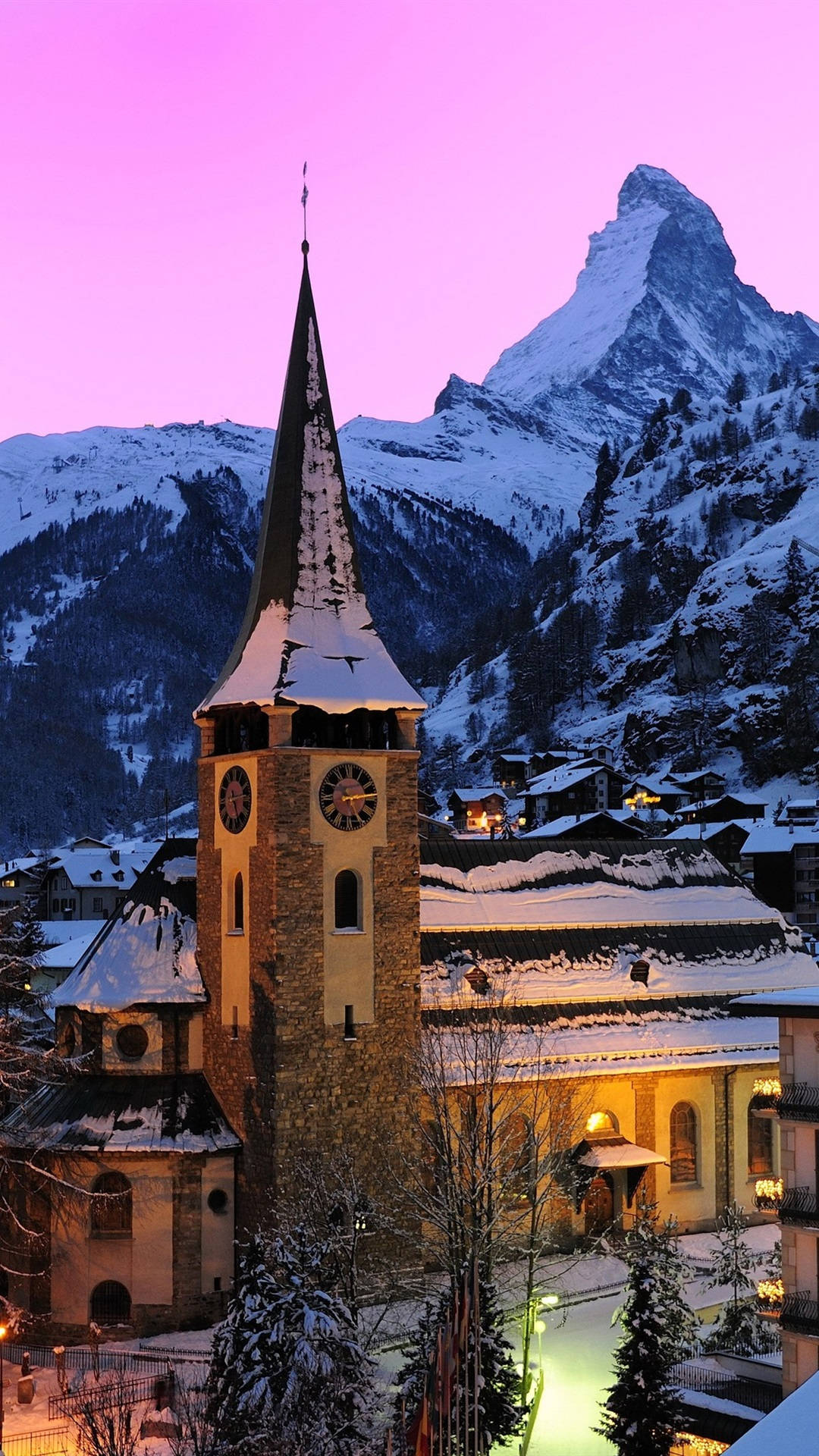 Alps 桌布 壁紙 — 被雪覆蓋的教堂塔樓在紫色暮色天空中溫暖地發光，背後是標誌性的馬特洪峰。