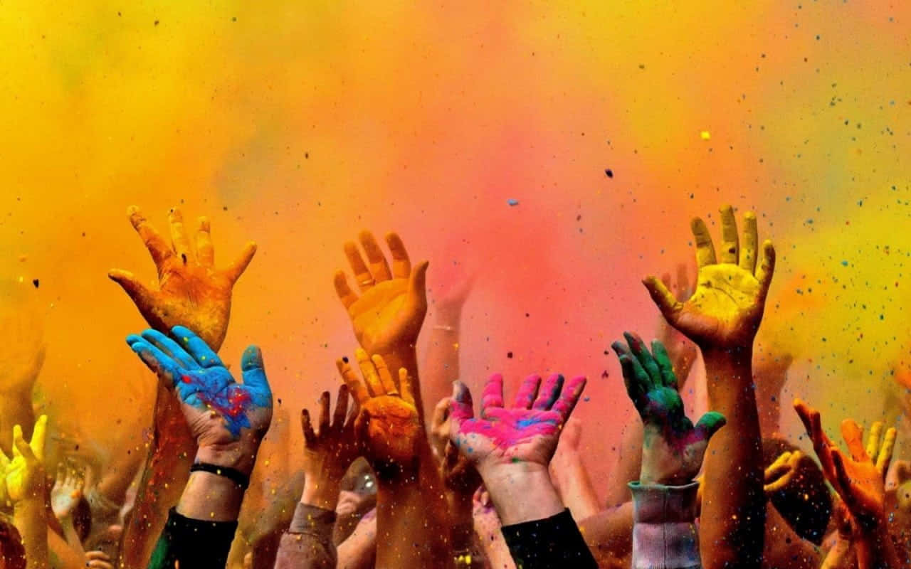 Holi 桌布 壁紙 — 被鮮豔粉末覆蓋的雙手向上伸展，背景是旋轉的橙色和黃色。