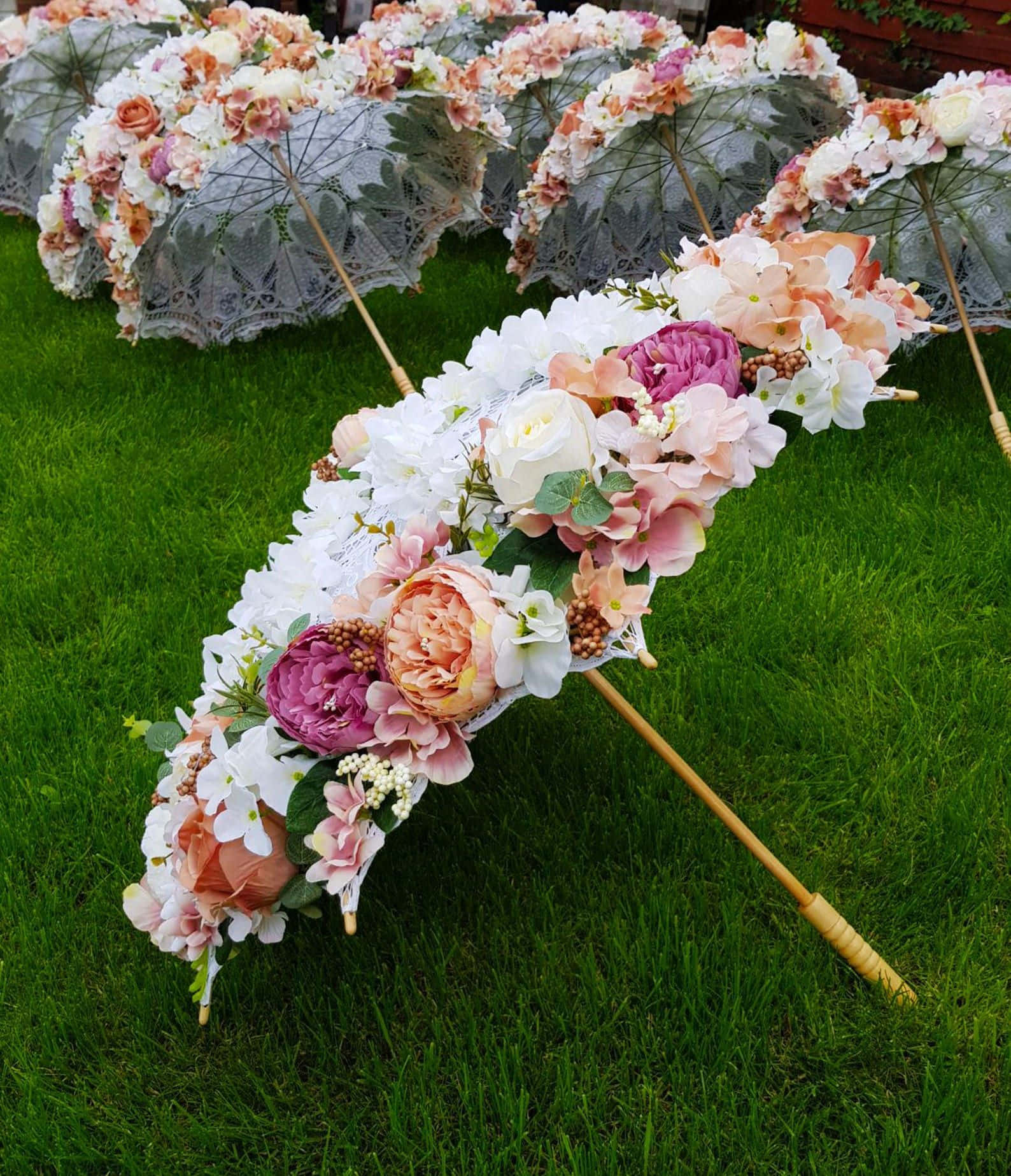 Umbrella 桌布 壁紙 — 裝飾性花卉傘，飾有蕾絲和粉彩花朵，放置在花園中充滿活力的綠色草地上。